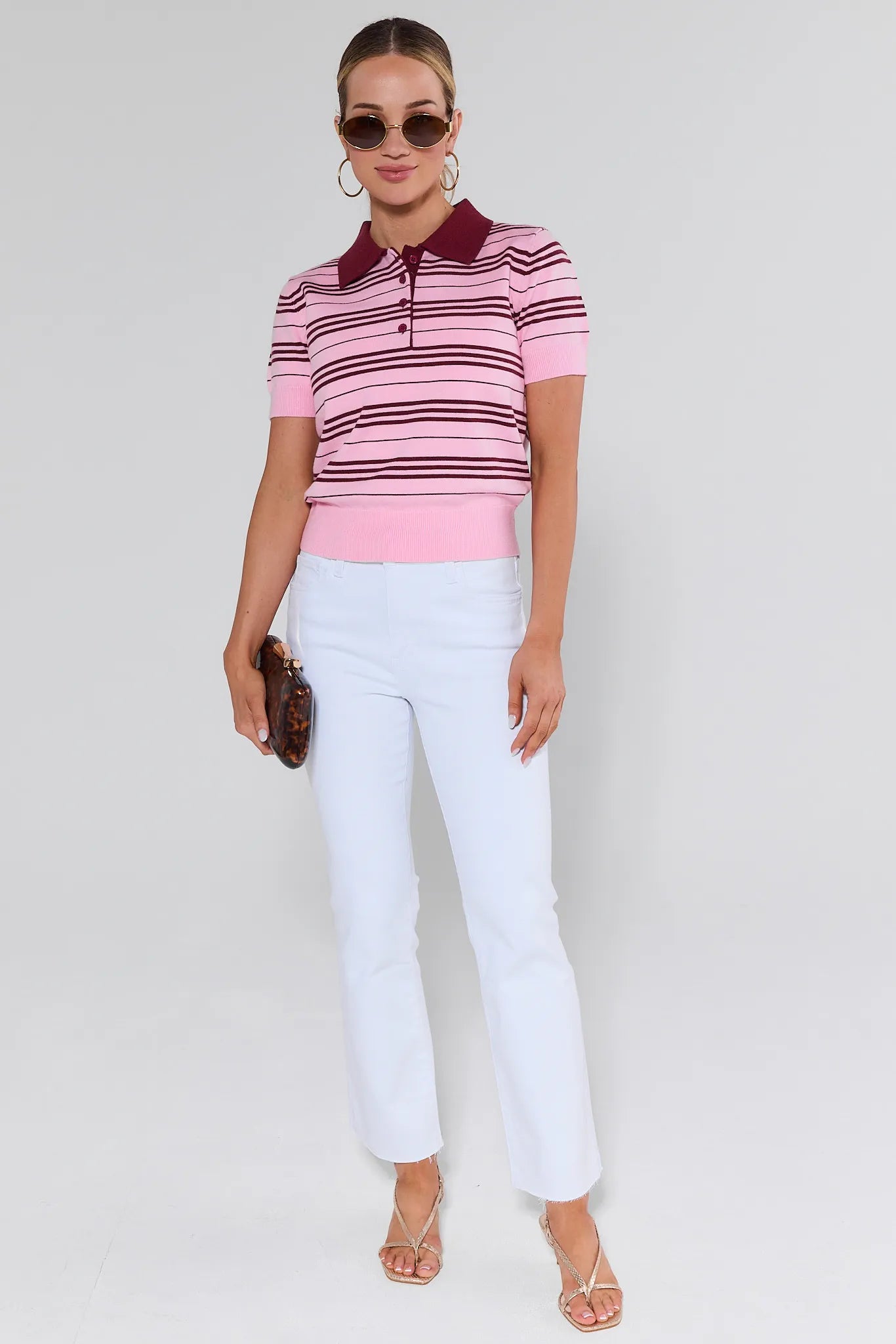Woman wearing a striped polo shirt and white pants on a plain background