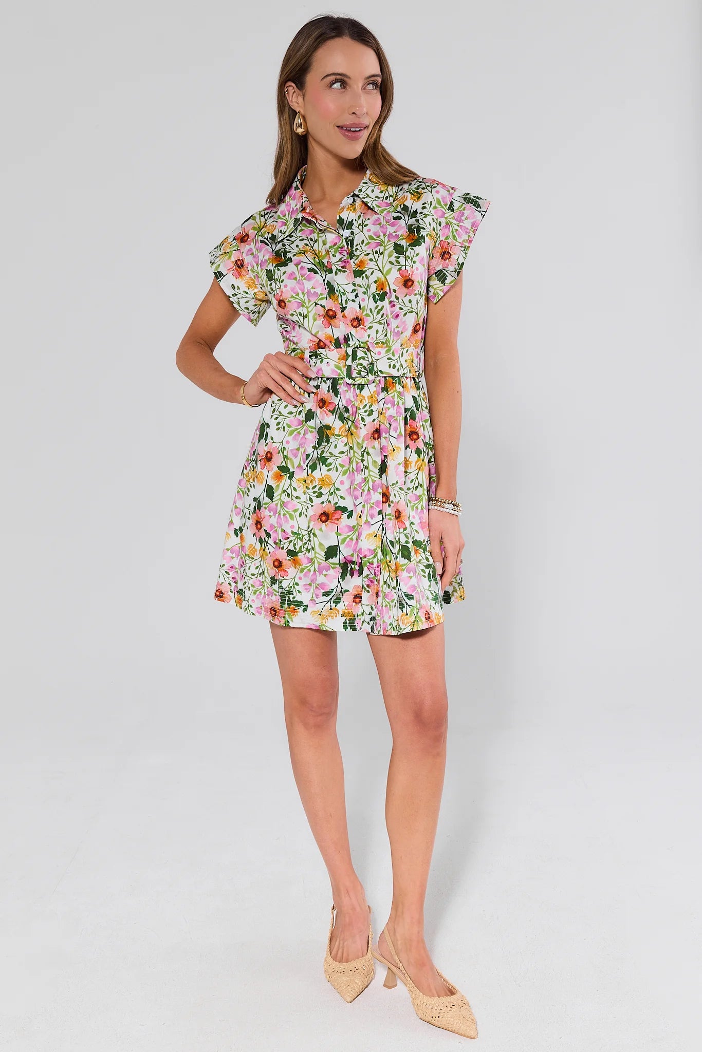 Woman wearing a floral dress and heels on a plain background