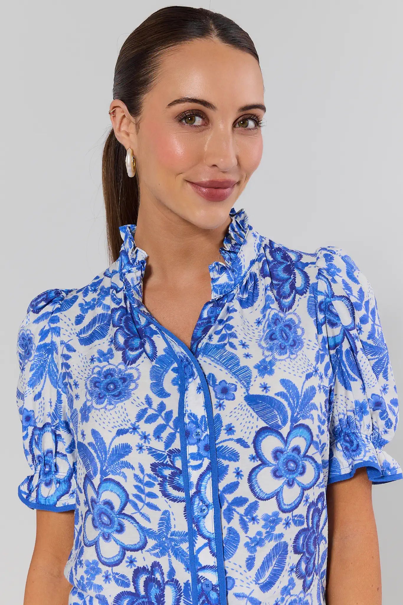 Woman wearing a blue floral blouse against a gray background