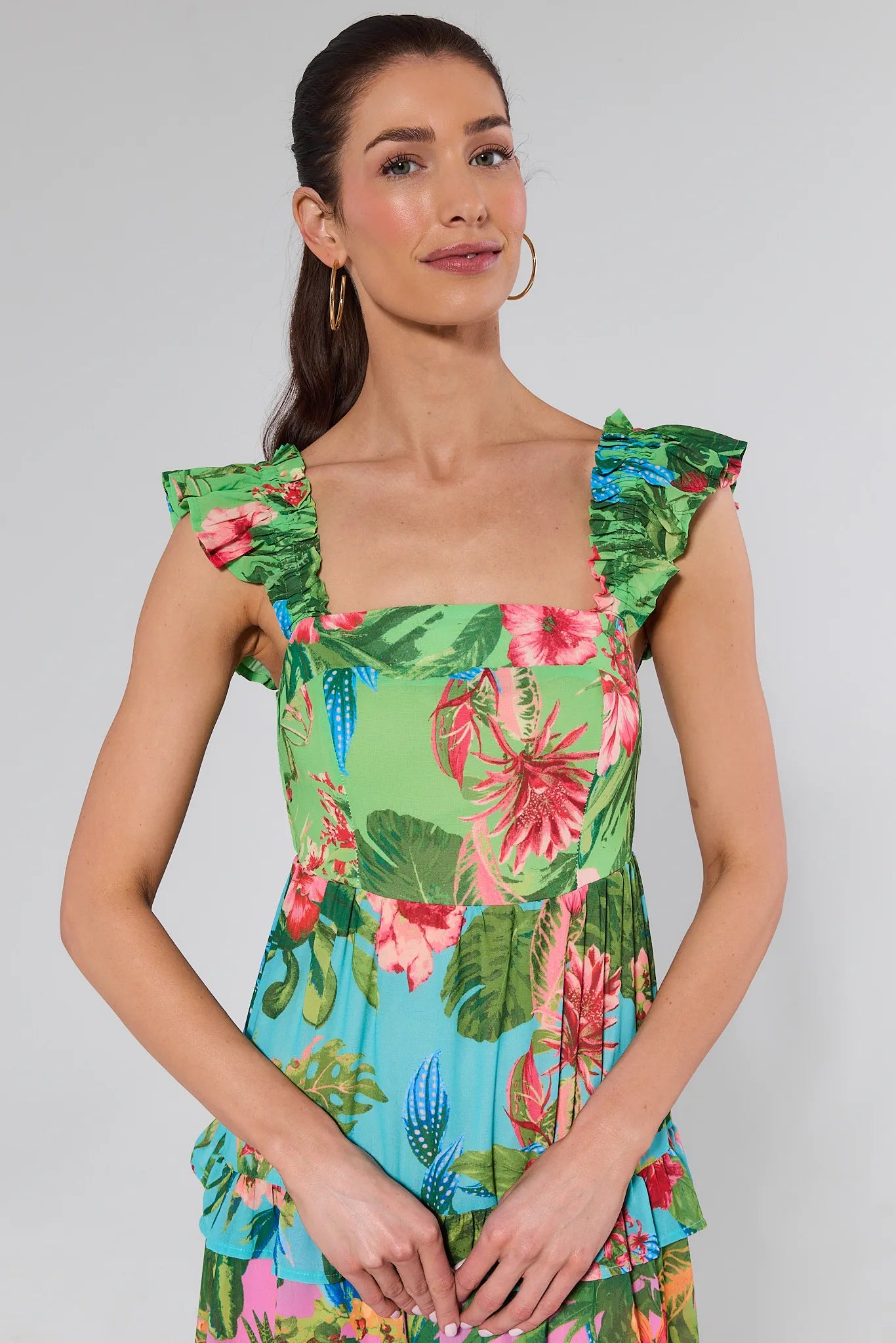 Woman wearing a colorful floral dress against a plain background