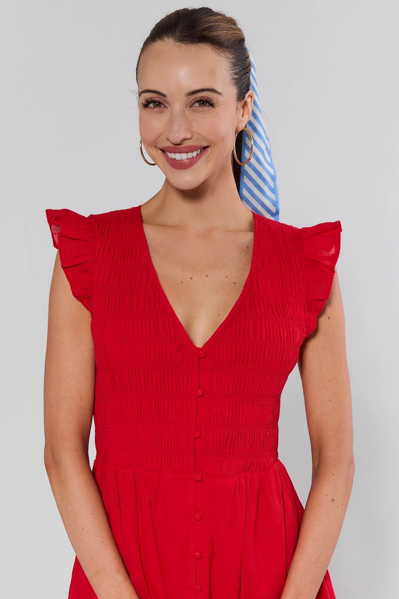 close up Woman wearing a red dress with ruffled sleeves against a plain background