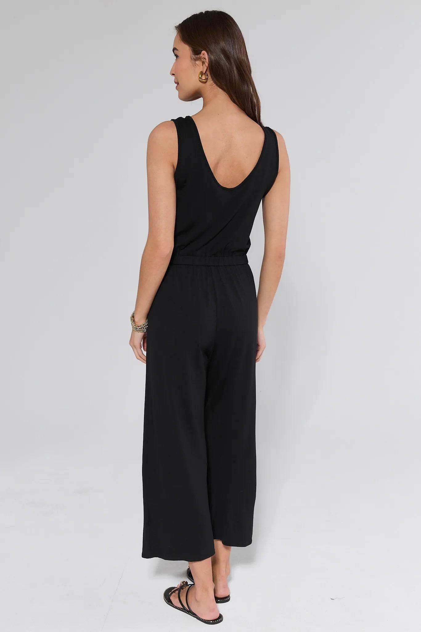 Woman wearing a black sleeveless top and wide-leg pants on a white background