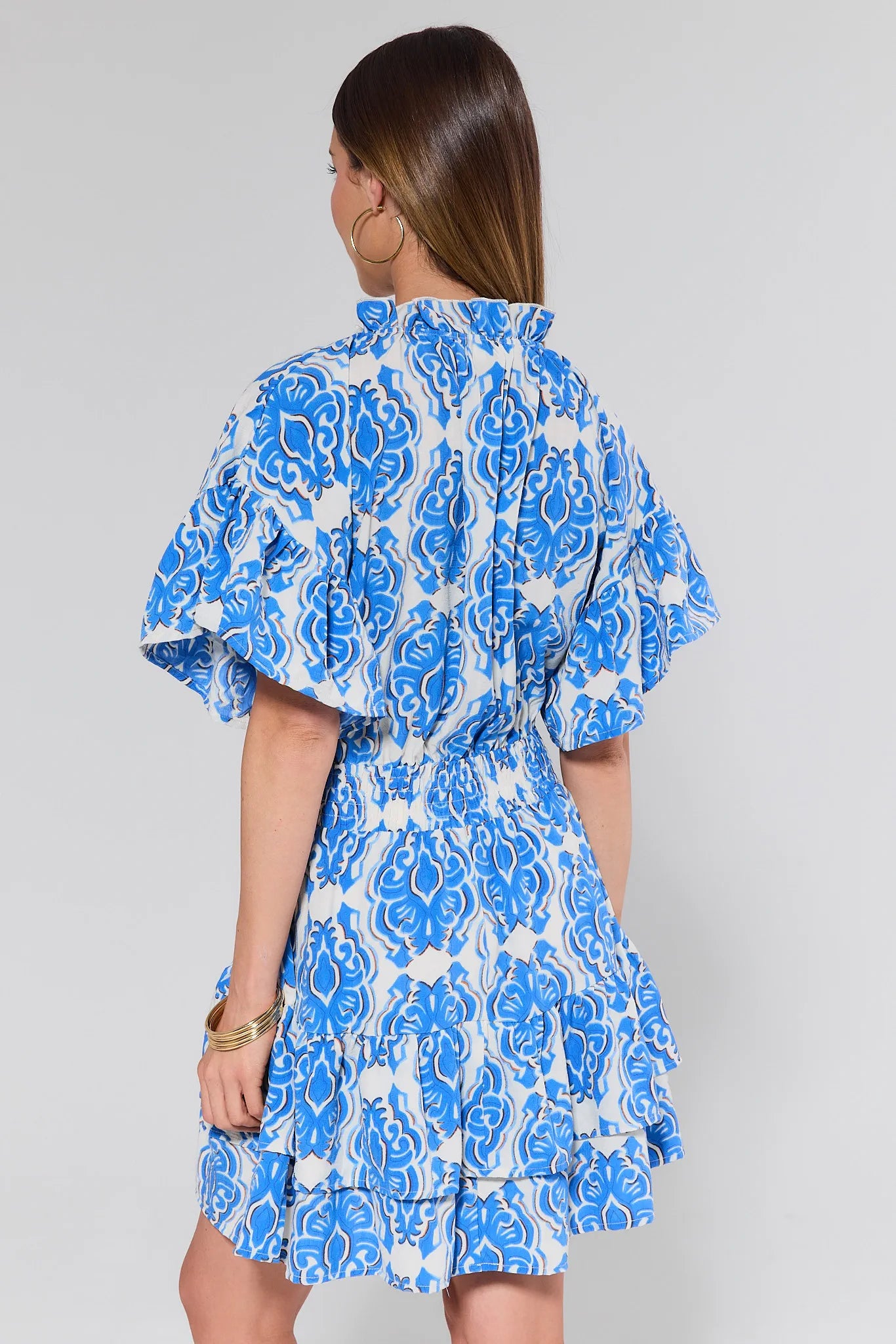 Woman wearing a blue and white patterned dress against a gray background