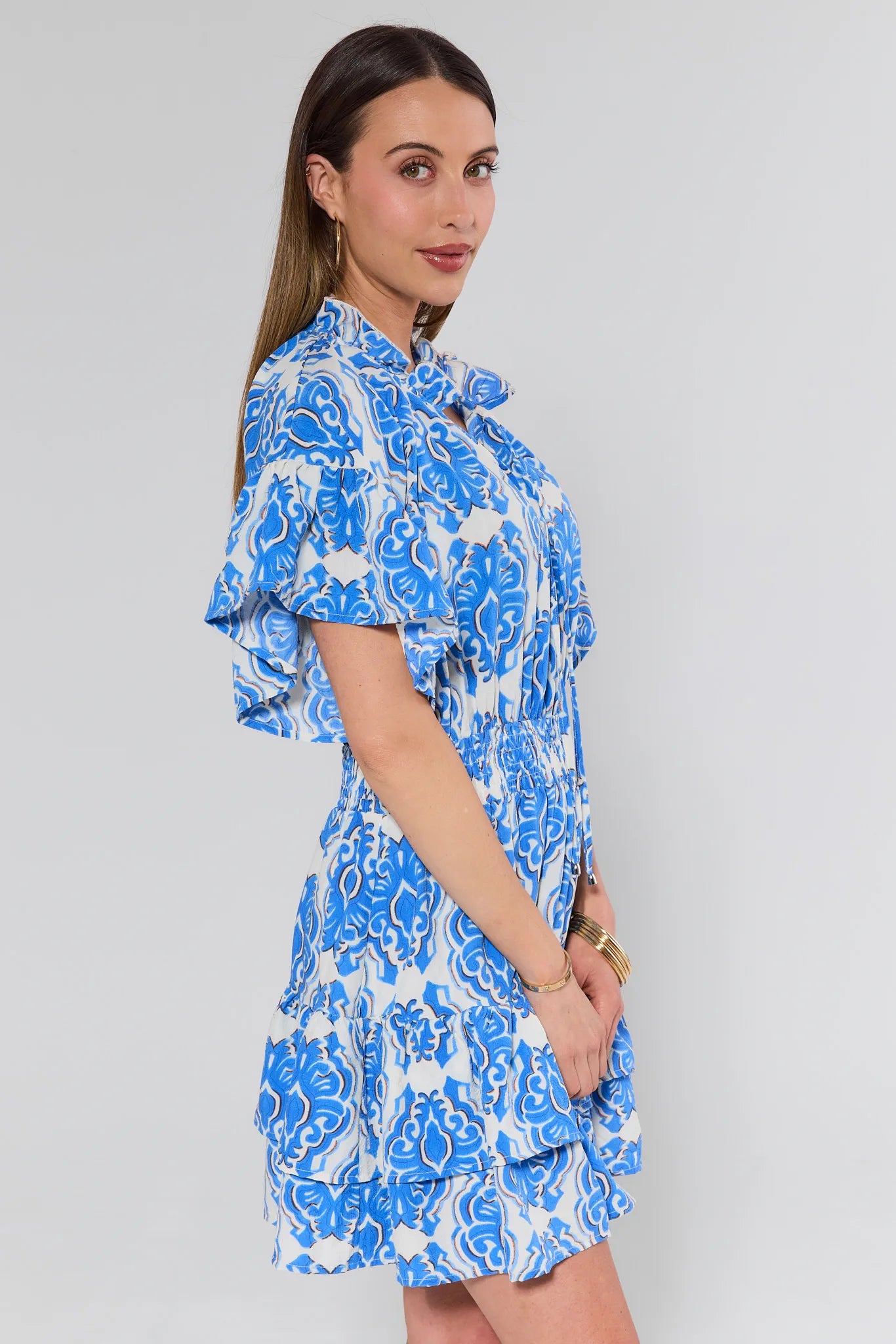 Woman wearing a blue and white patterned dress against a plain background
