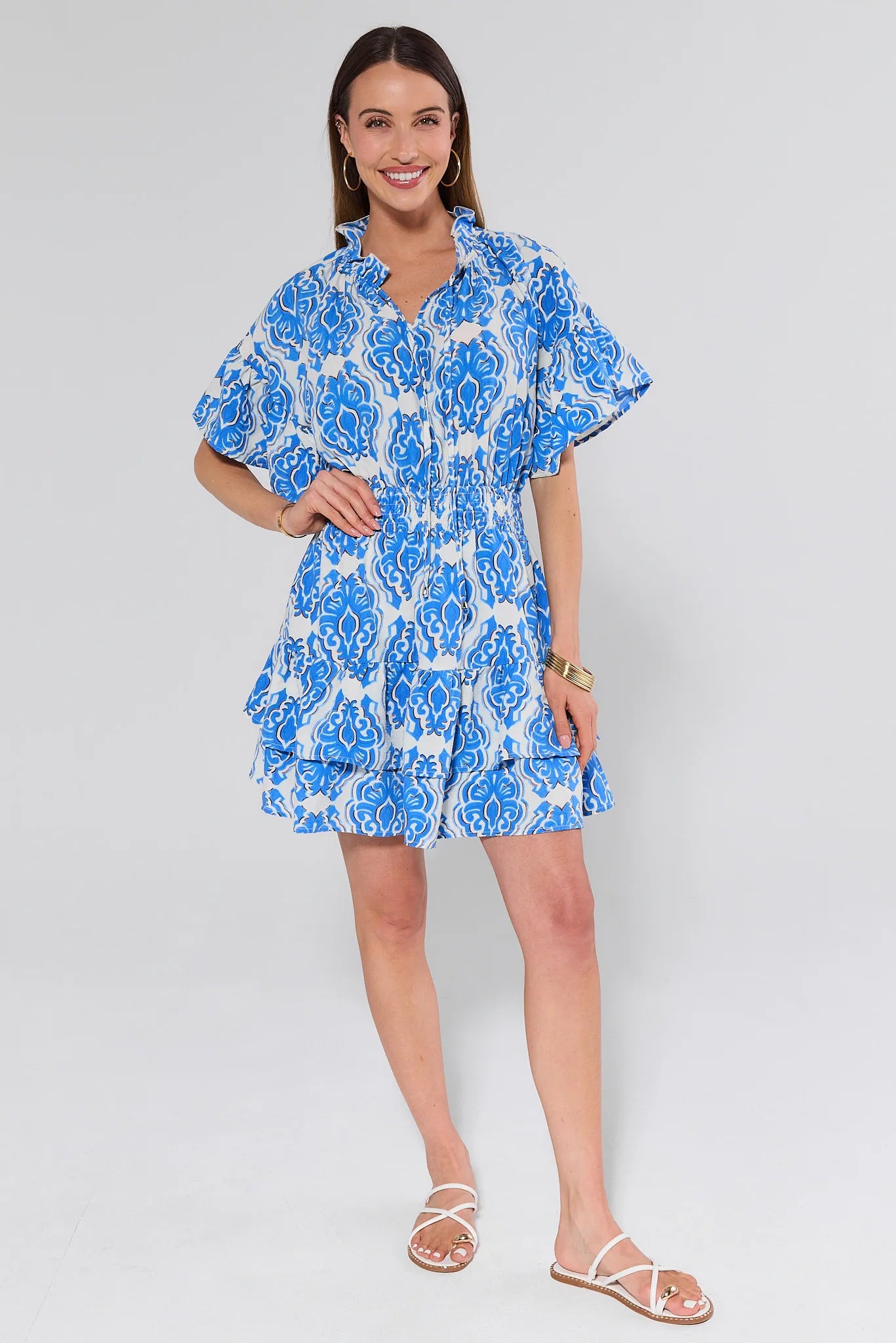 Woman wearing a blue and white floral dress on a plain background