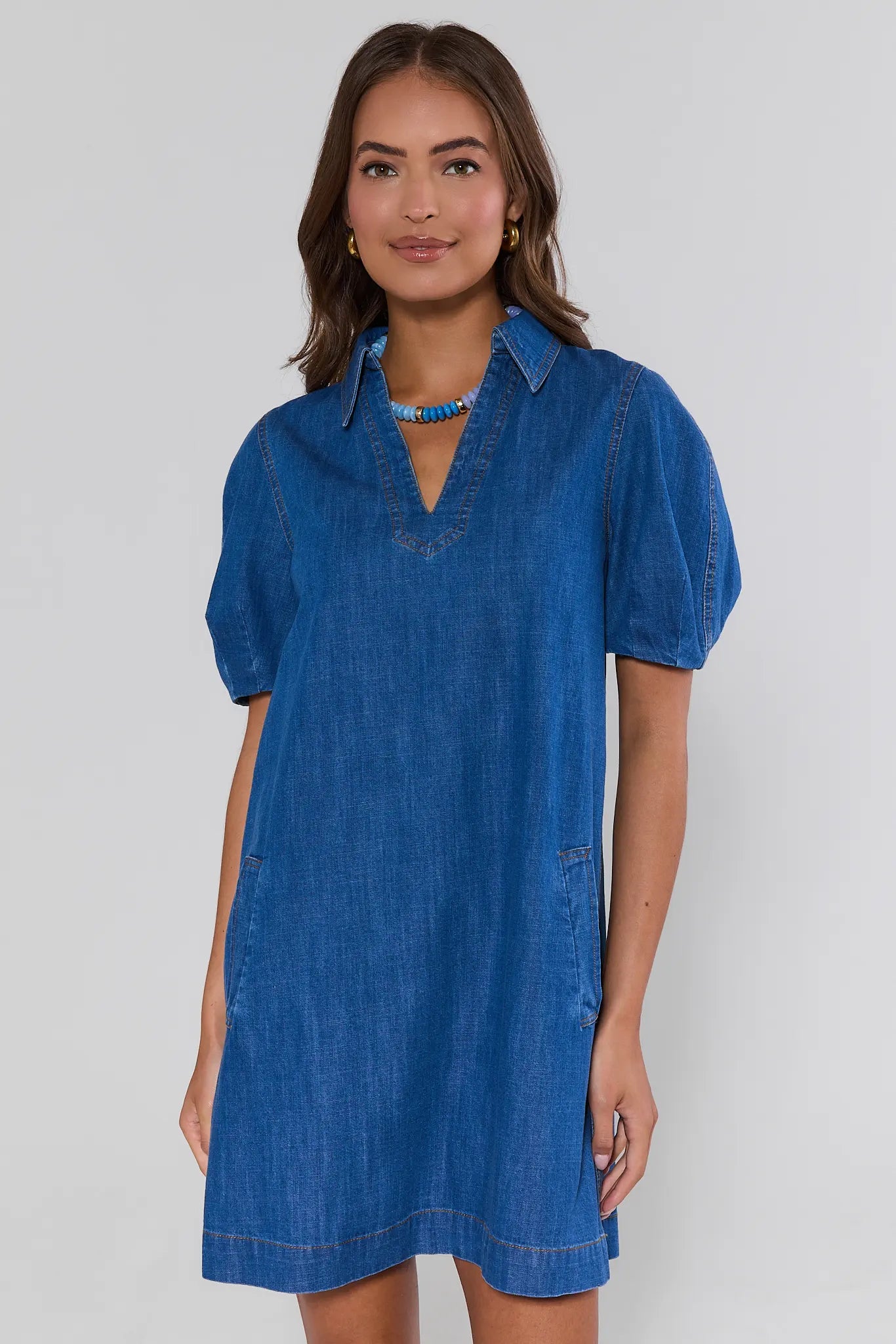 Woman wearing a blue denim dress against a white background