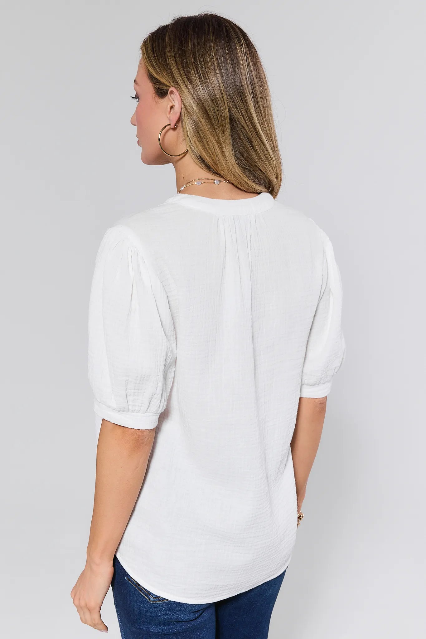 Woman wearing a white blouse and blue jeans on a plain background