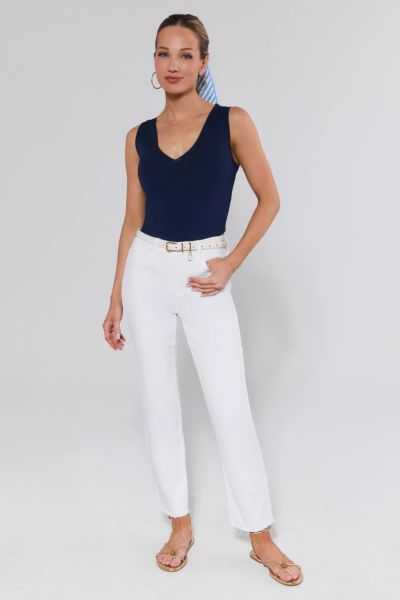 View 2: Woman wearing a navy sleeveless top and white pants on a plain background