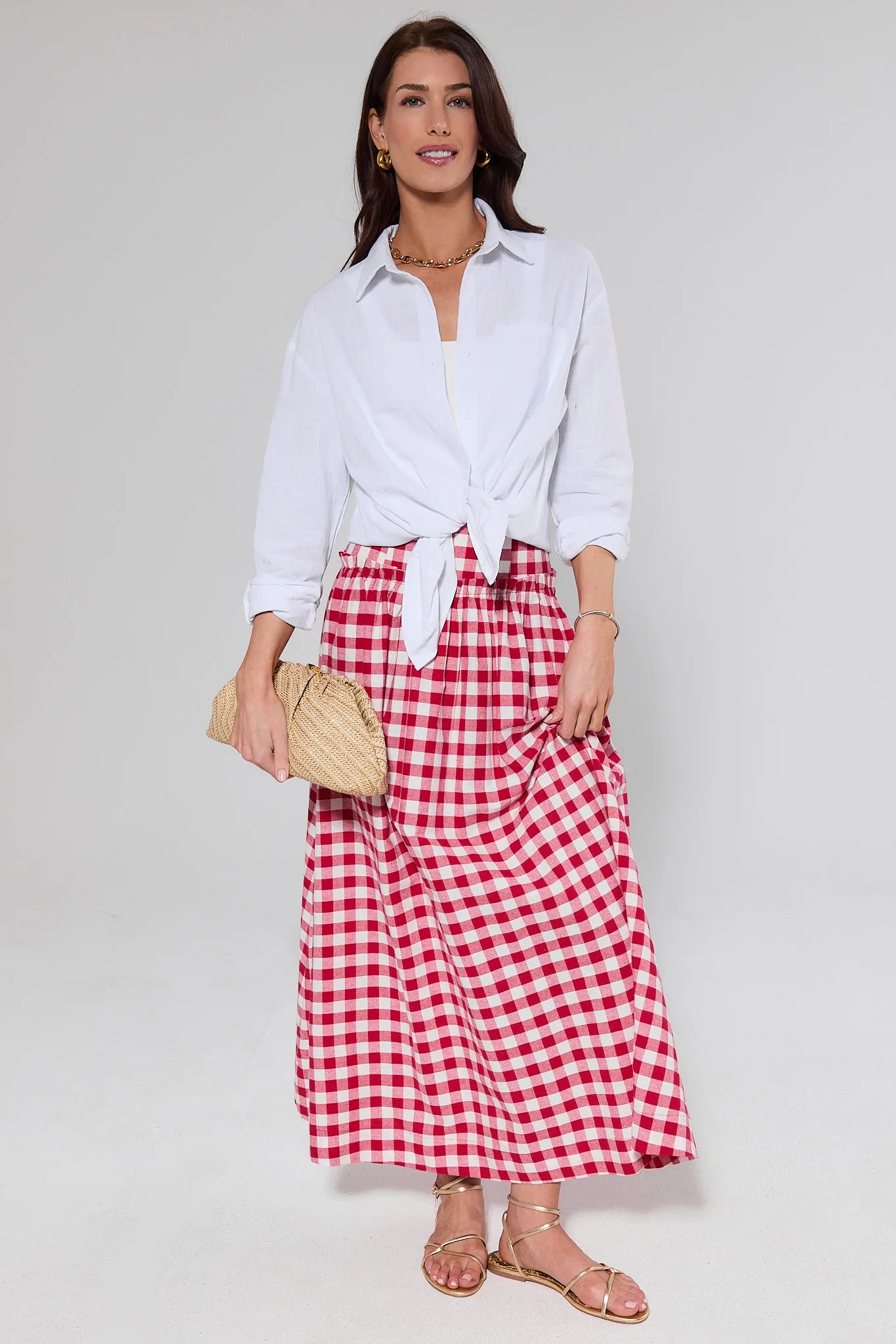 Woman wearing a white shirt and red checkered skirt on a plain background