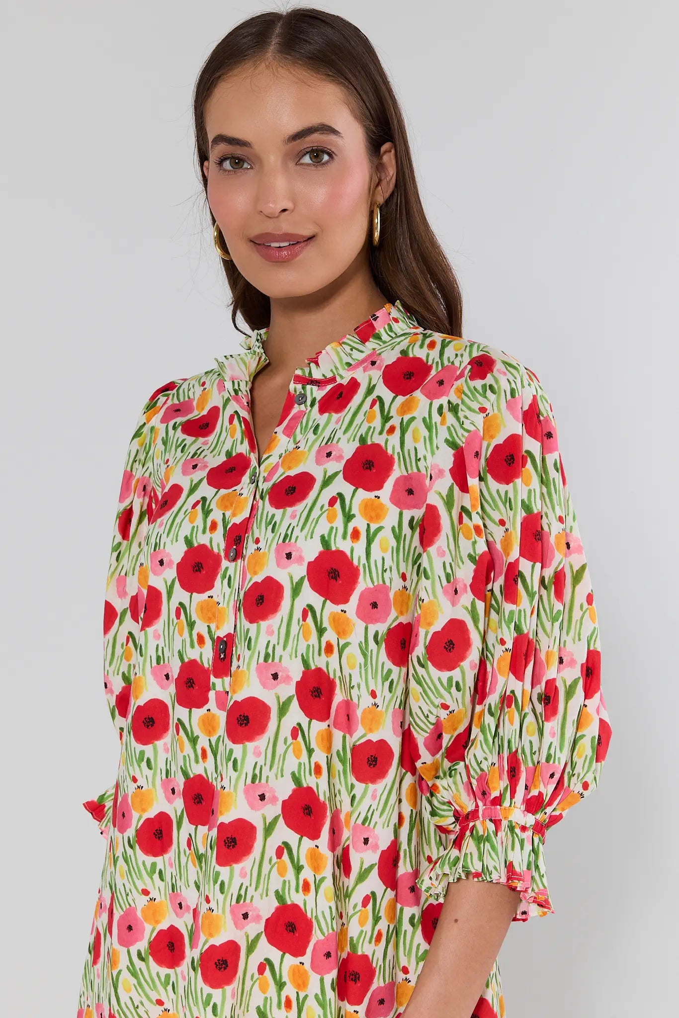 Woman wearing a colorful floral dress against a plain background
