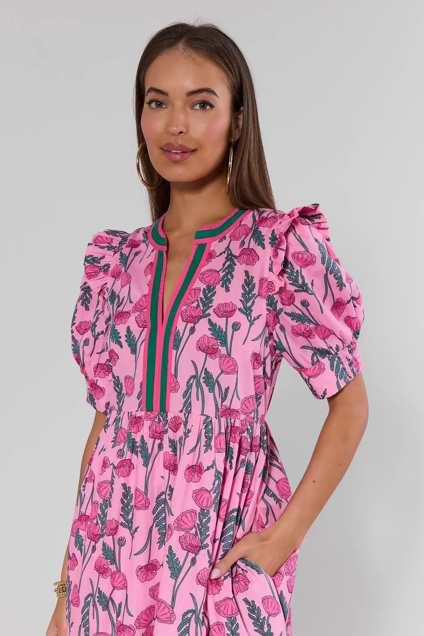 Woman wearing a pink floral dress with green accents on a plain background