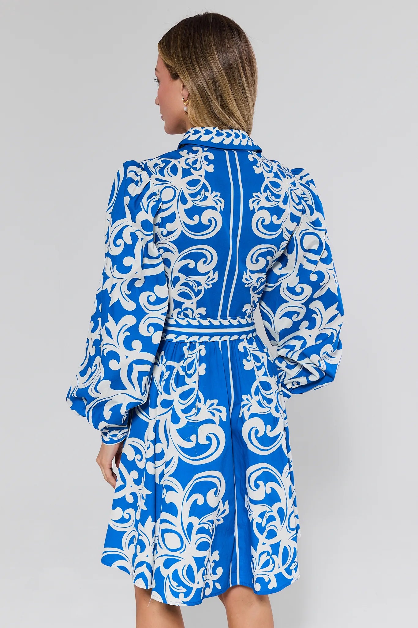 Woman wearing a blue and white patterned dress against a gray background