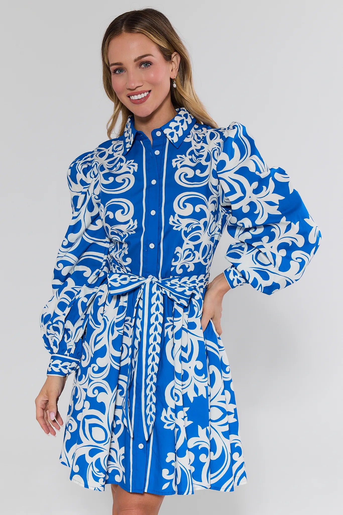 Woman wearing a blue and white patterned dress on a plain background