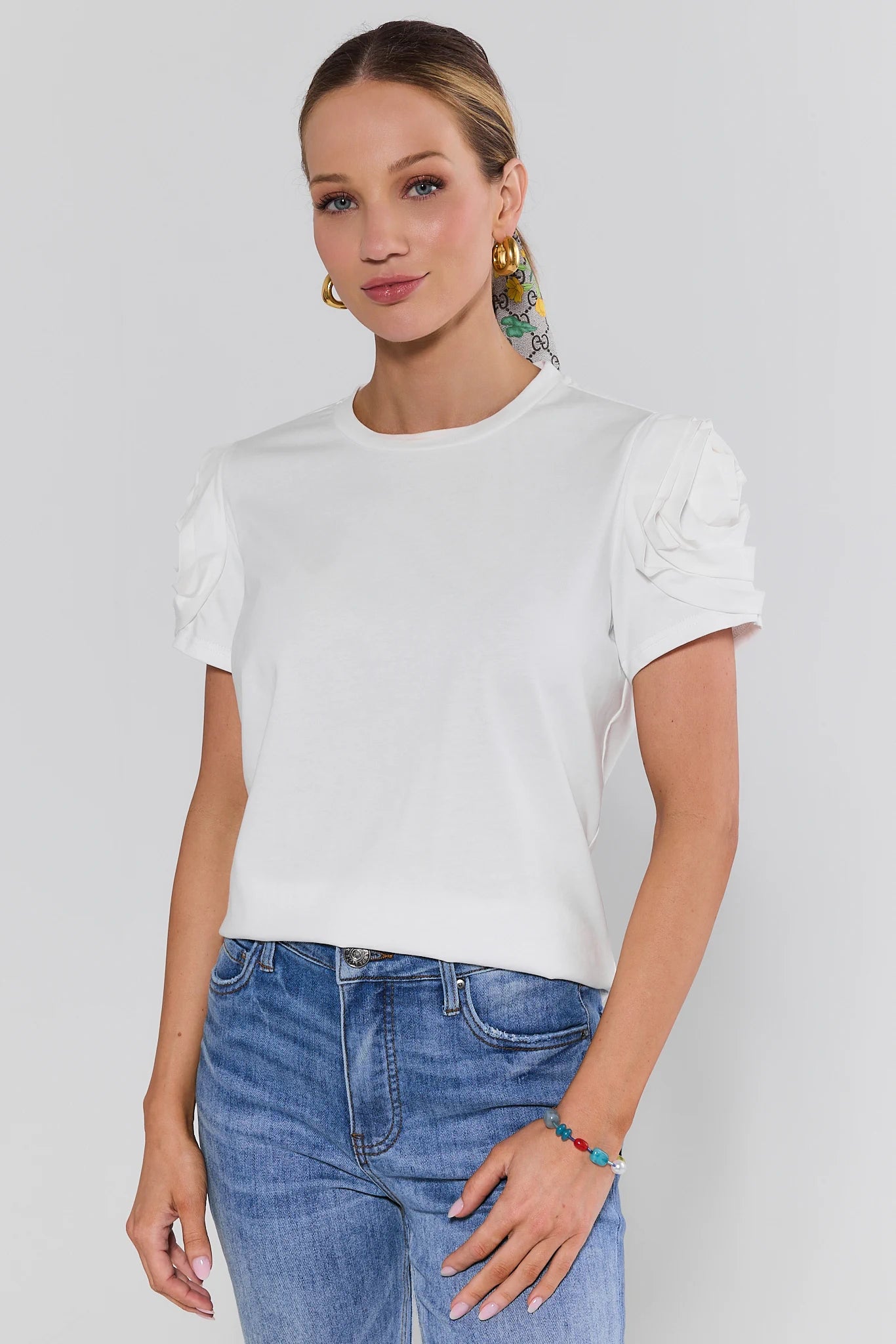 Woman wearing a white t-shirt and blue jeans against a plain background