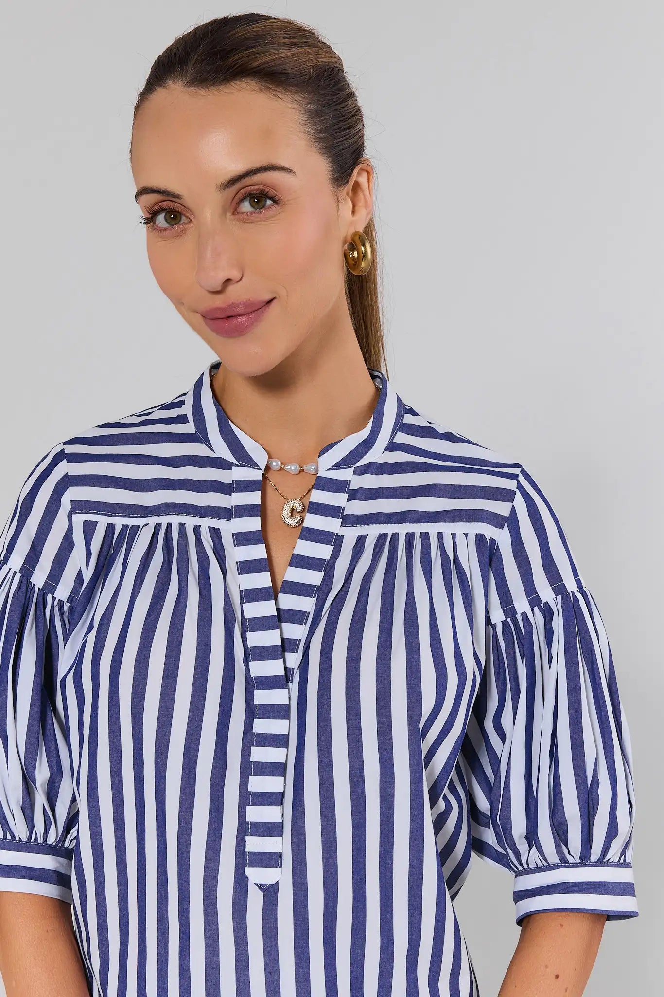 close up Woman wearing a blue and white striped shirt against a gray background