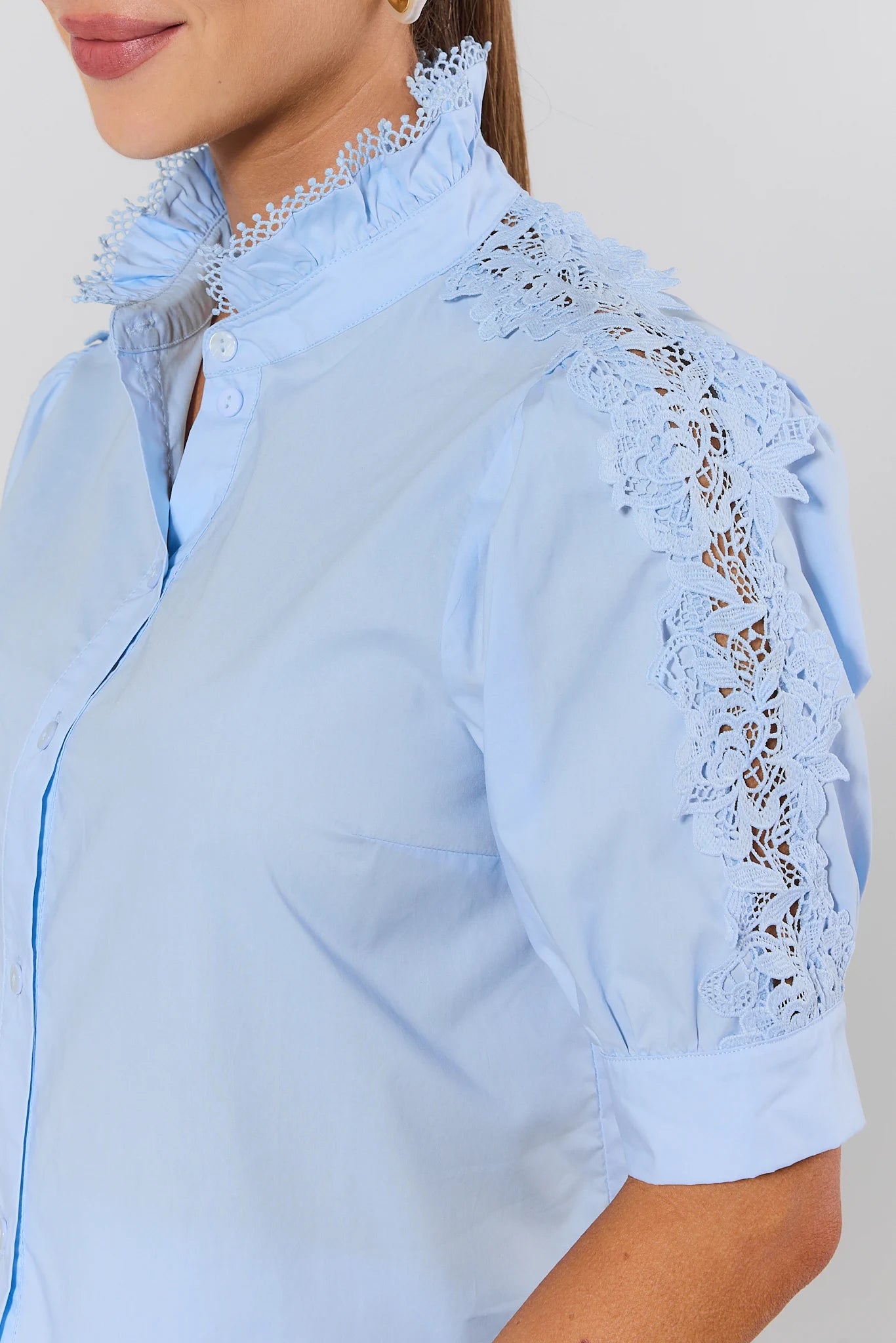 Light blue blouse with lace detailing on a plain background