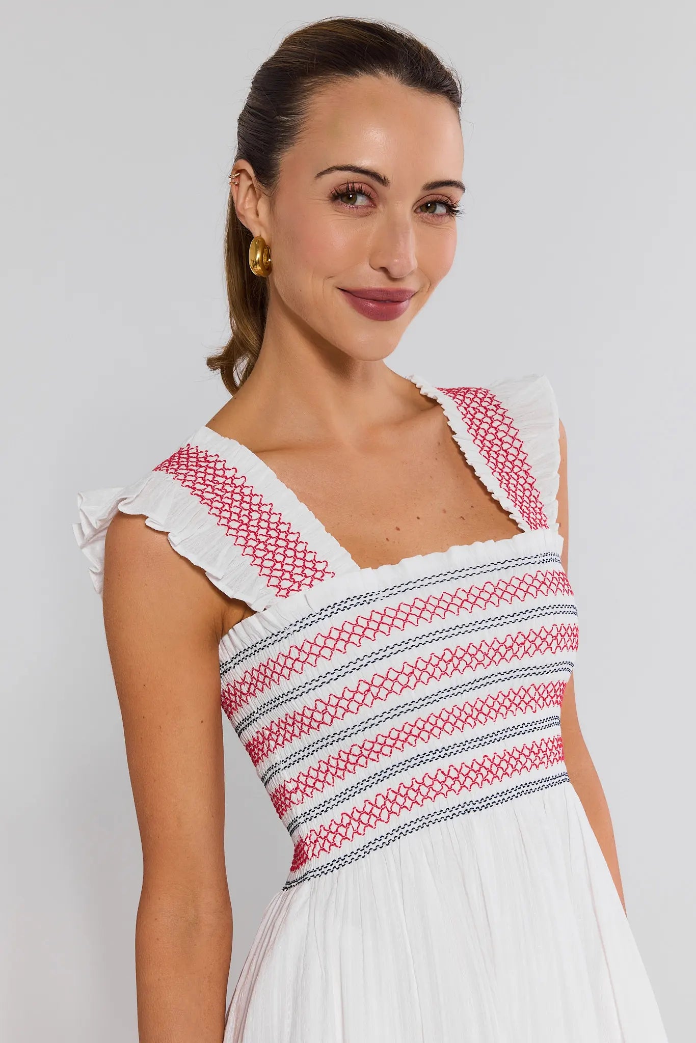 close up Woman wearing a white dress with red and blue patterns on a plain background