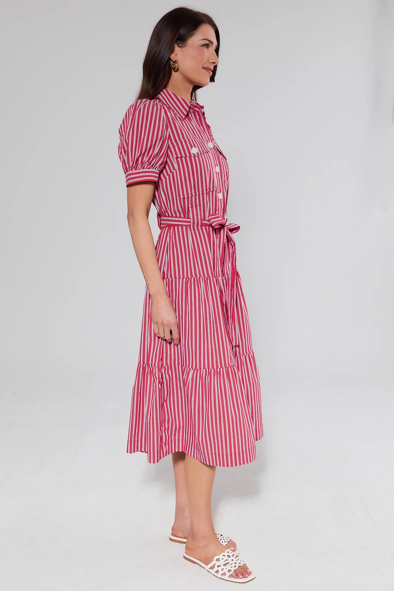 side shot Woman wearing a red and white striped dress on a plain background
