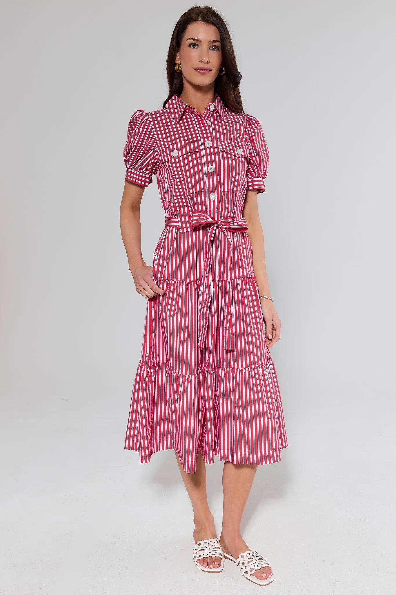 Woman wearing a red and white striped dress and white sandals on a gray background