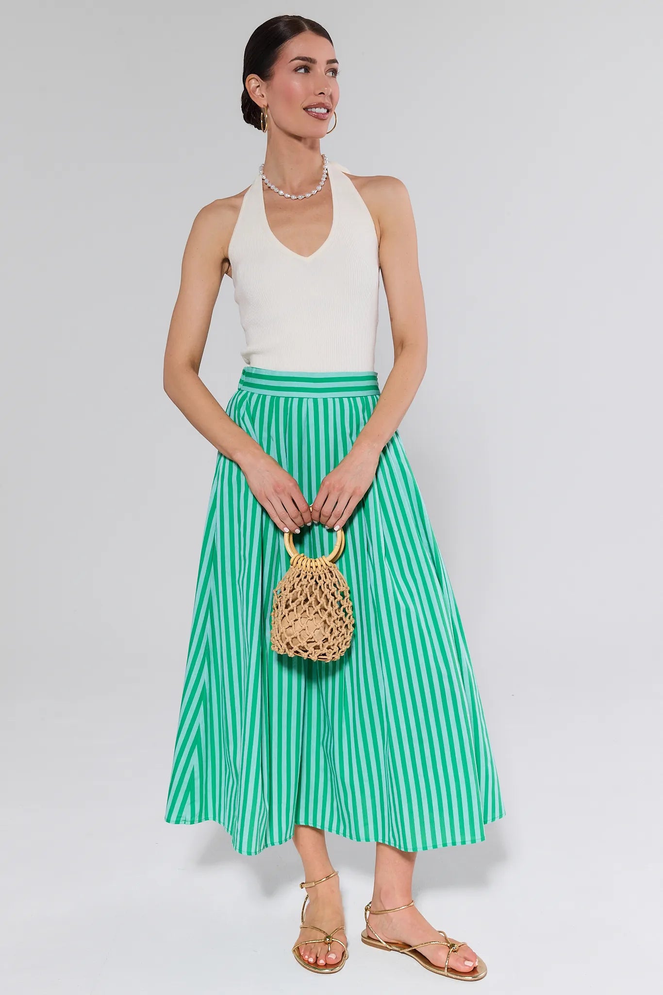 women wearing green and green stripe skirt and white tank on white background
