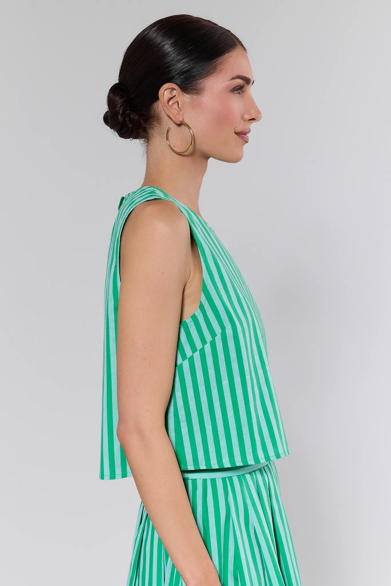 Woman wearing a green and white striped dress against a plain background