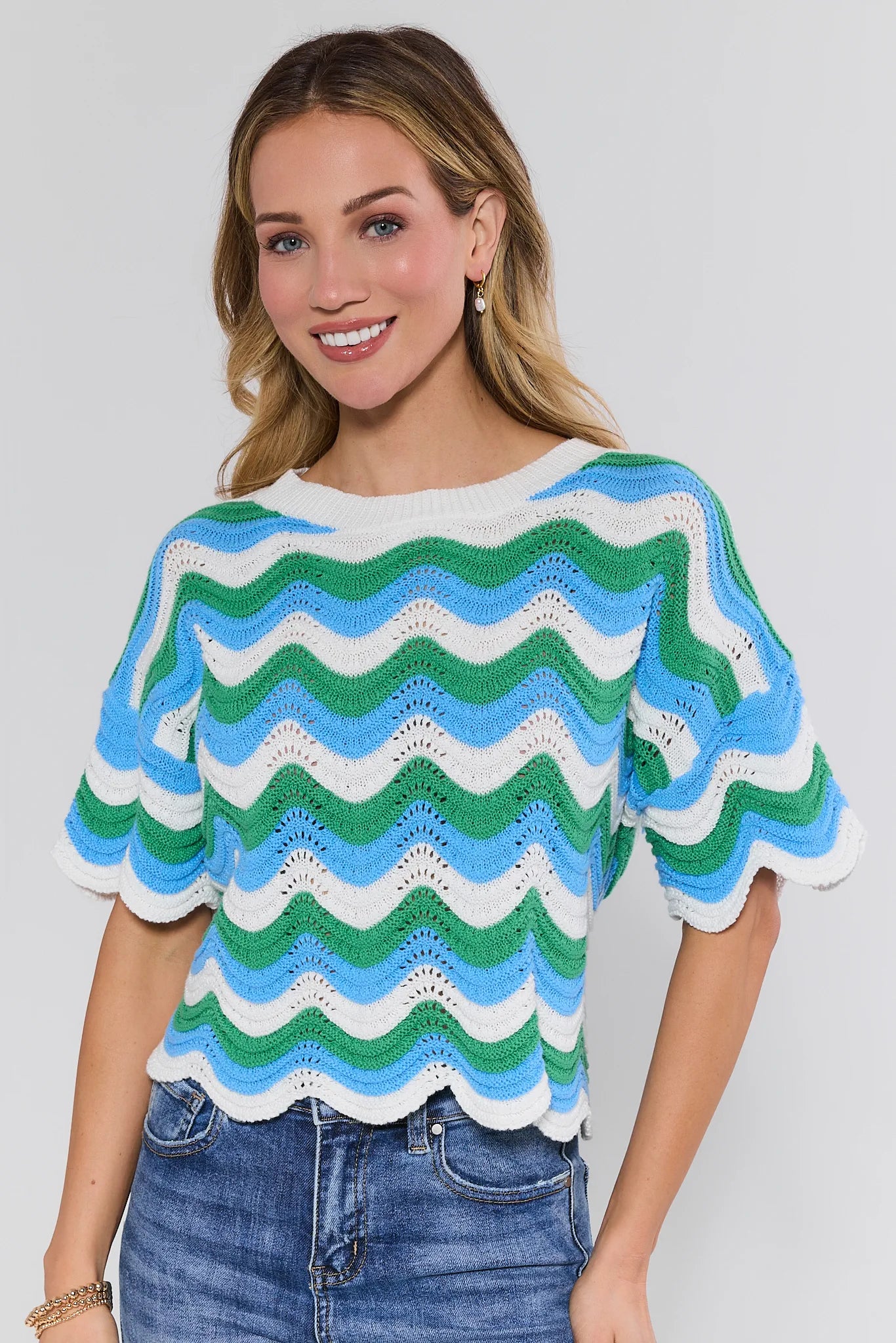 Woman wearing a colorful wavy patterned sweater against a plain background