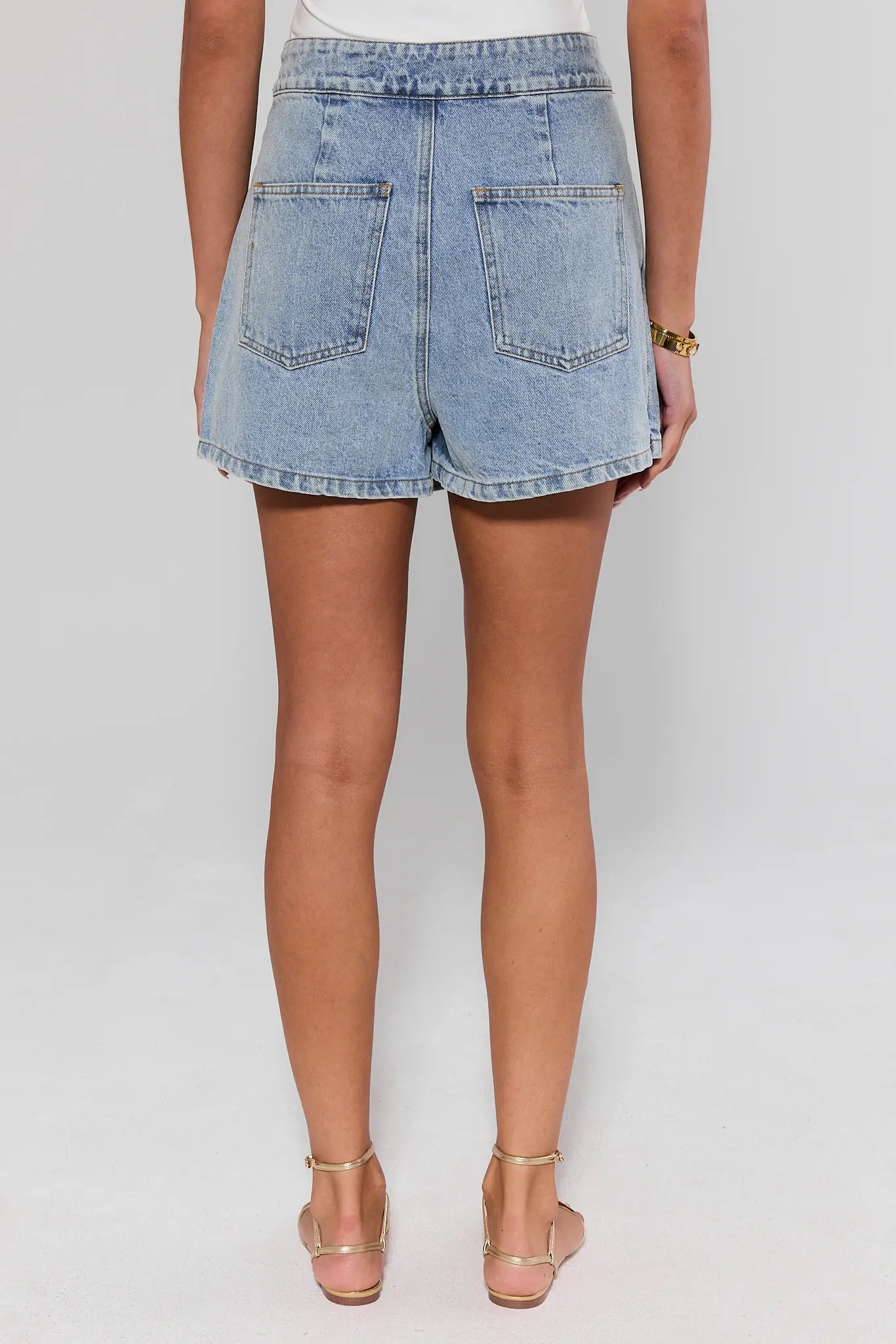 Denim shorts worn by a person standing on a plain background