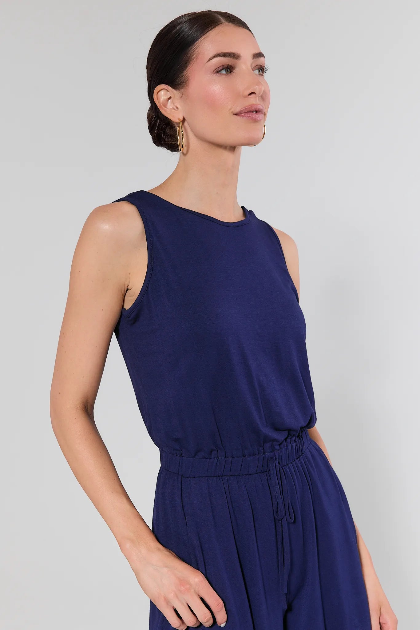 Woman wearing a sleeveless navy blue dress against a plain background