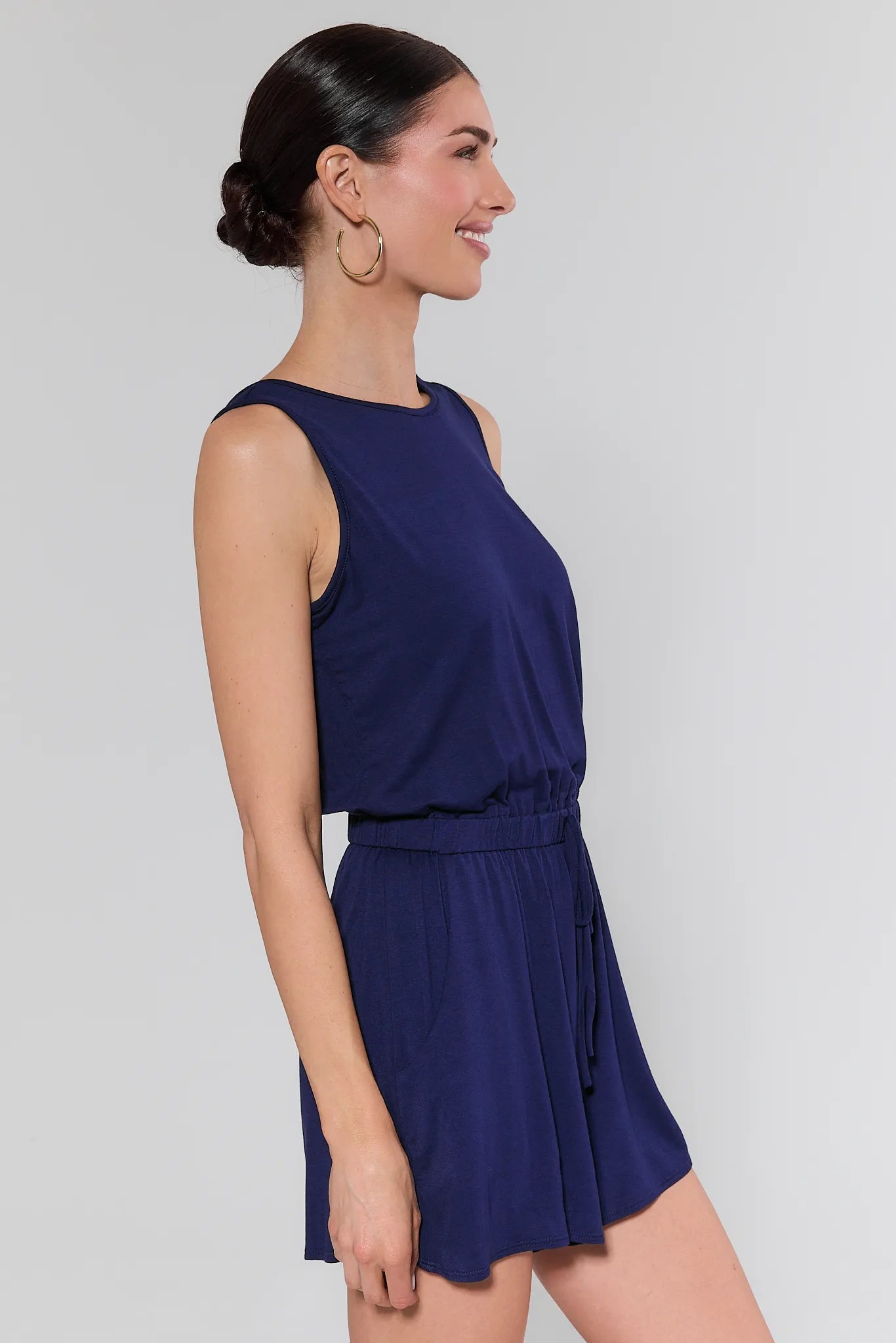 Woman wearing a navy blue sleeveless dress against a plain background