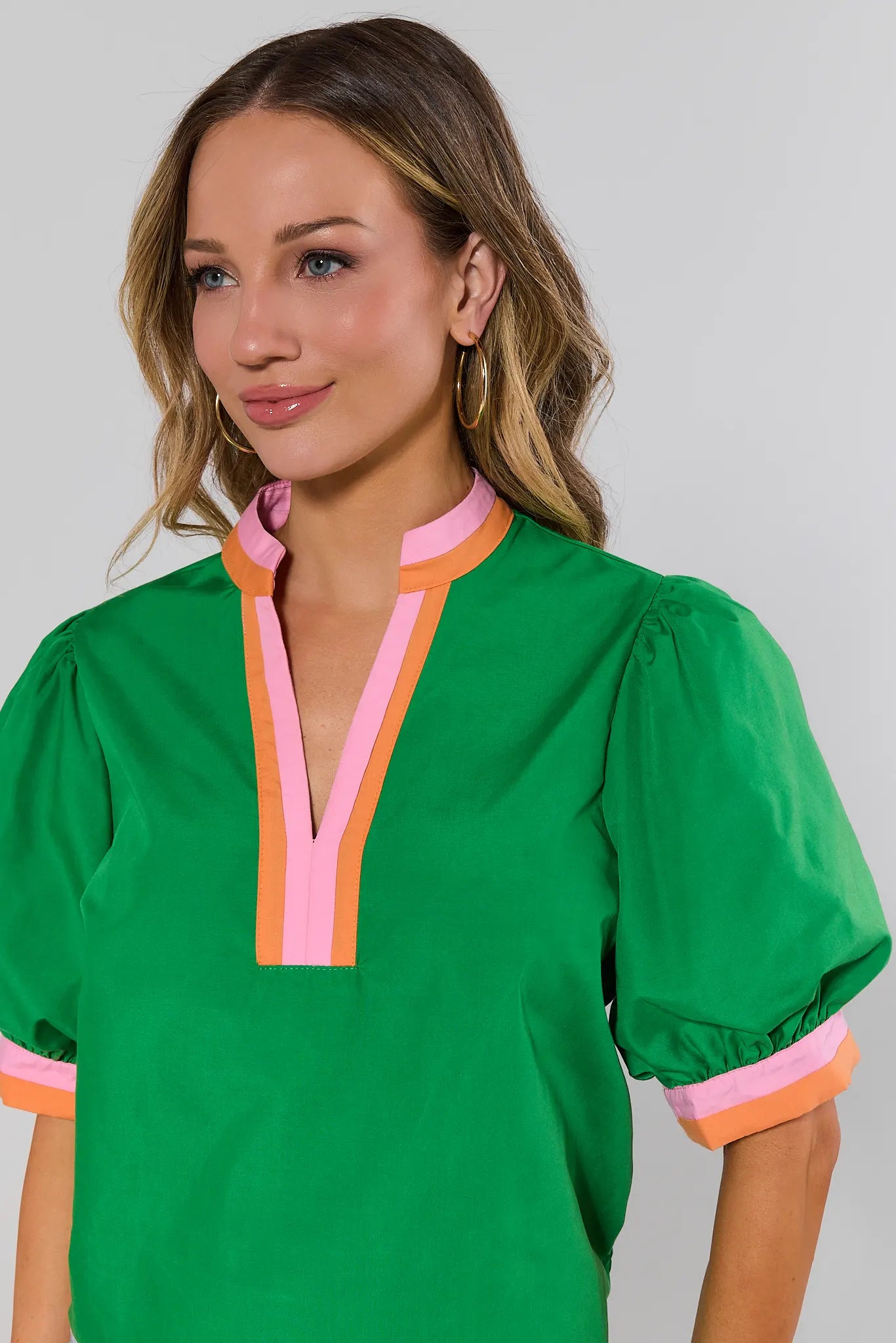 close up Woman wearing a green blouse with colorful trim on a plain background