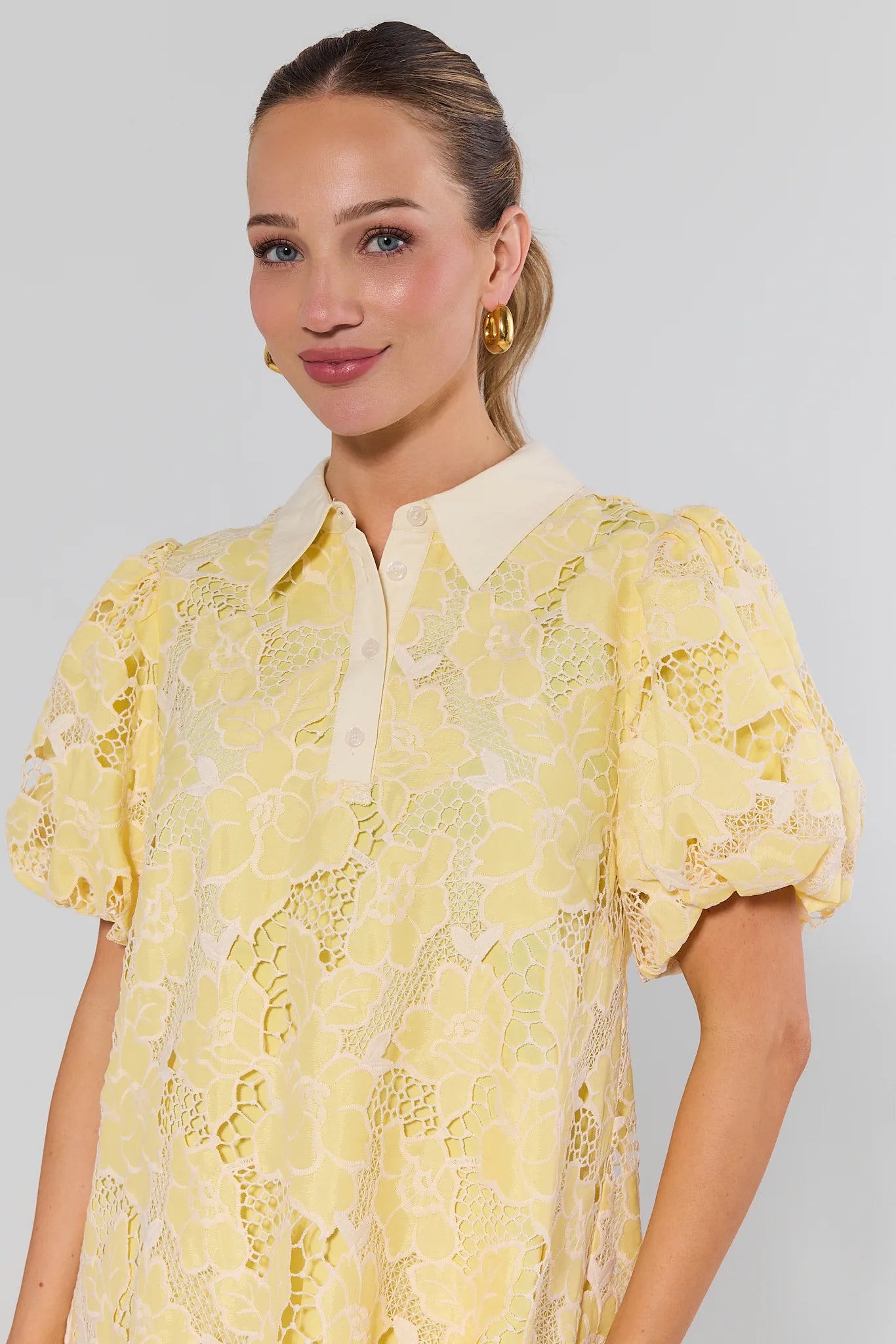 Woman wearing a yellow lace dress against a background