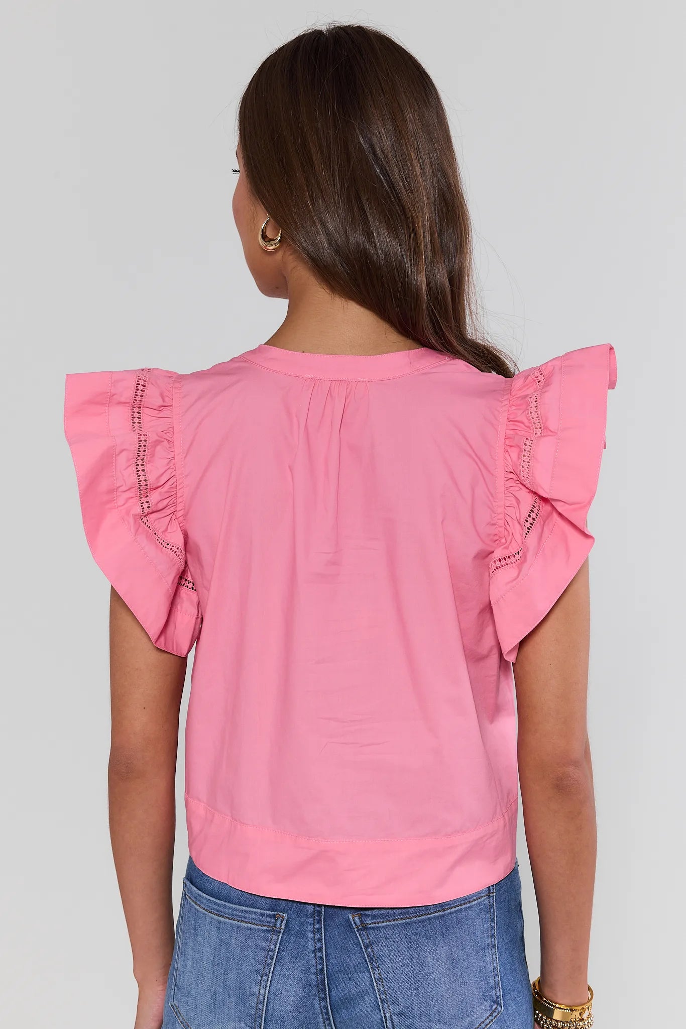 Pink blouse with ruffled sleeves worn by a person on a plain background