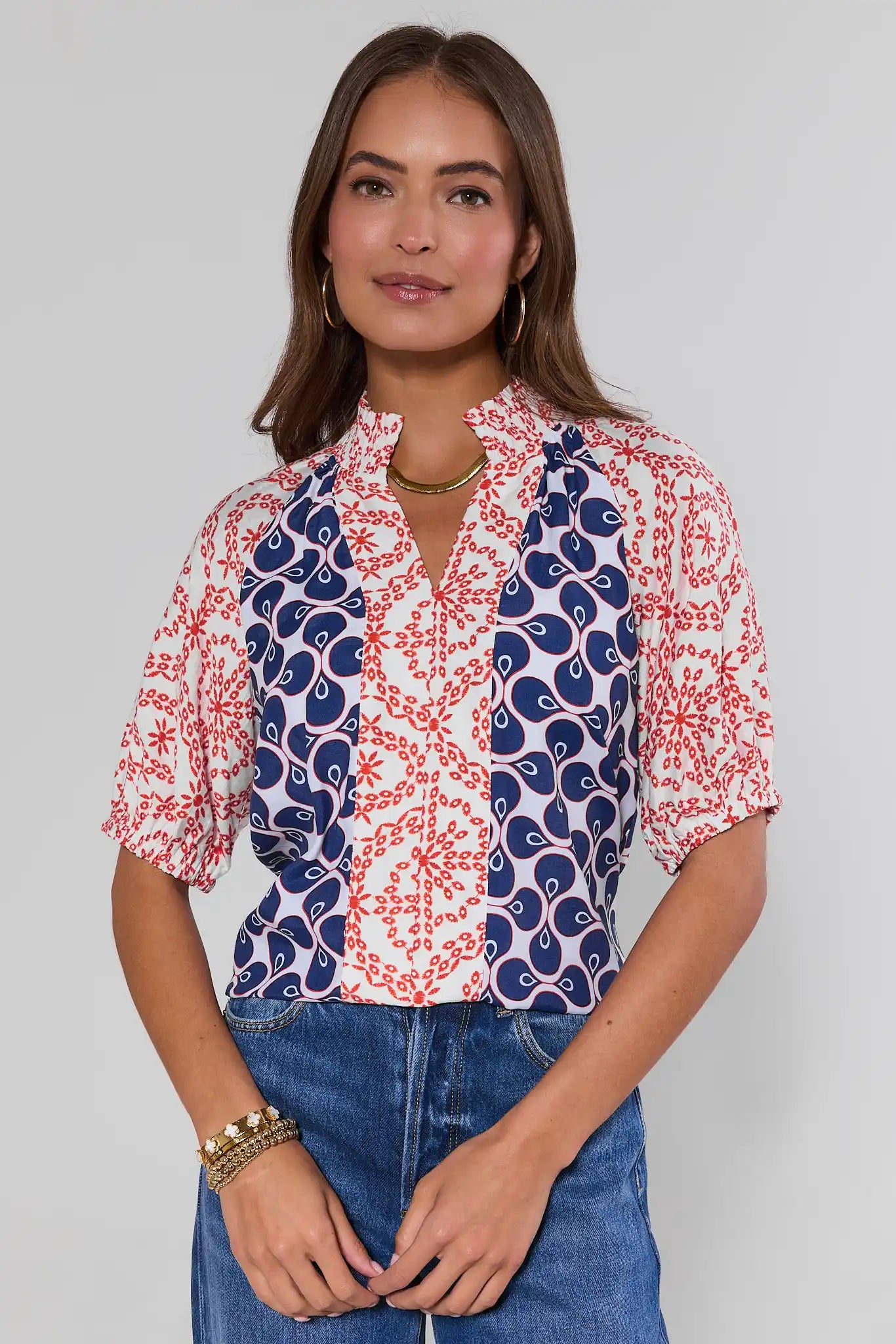 Woman wearing a patterned blouse with blue and red design on a plain background
