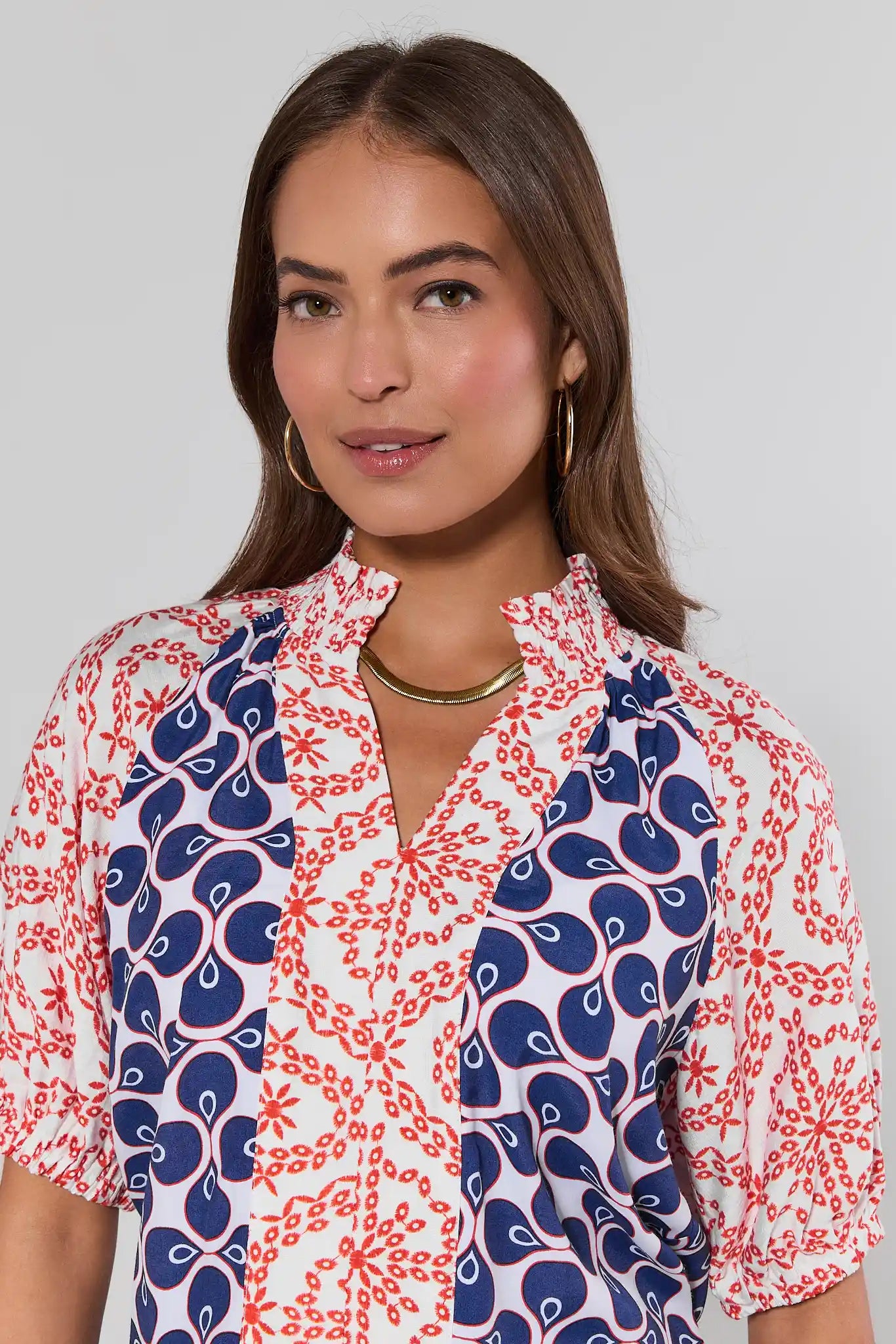 close up Woman wearing a patterned shirt with blue and red designs on a plain background