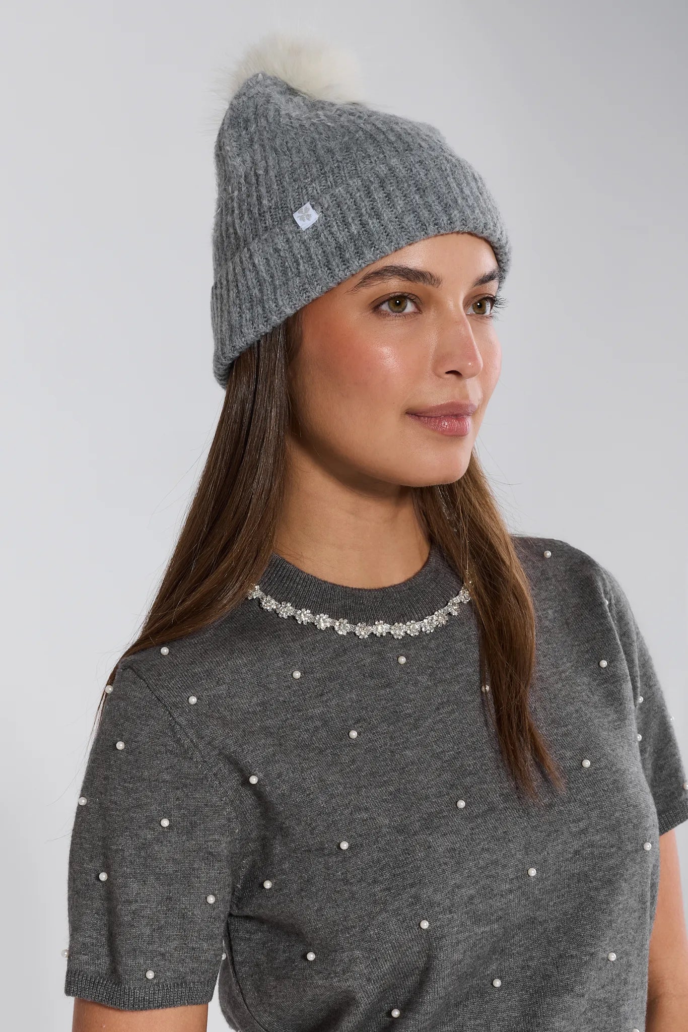 Woman wearing a Darla Gray Pom Pom Beanie on a light gray background