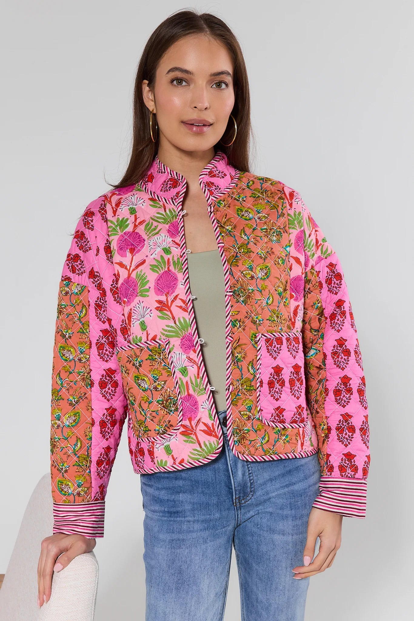 Woman wearing a colorful floral jacket on a plain background