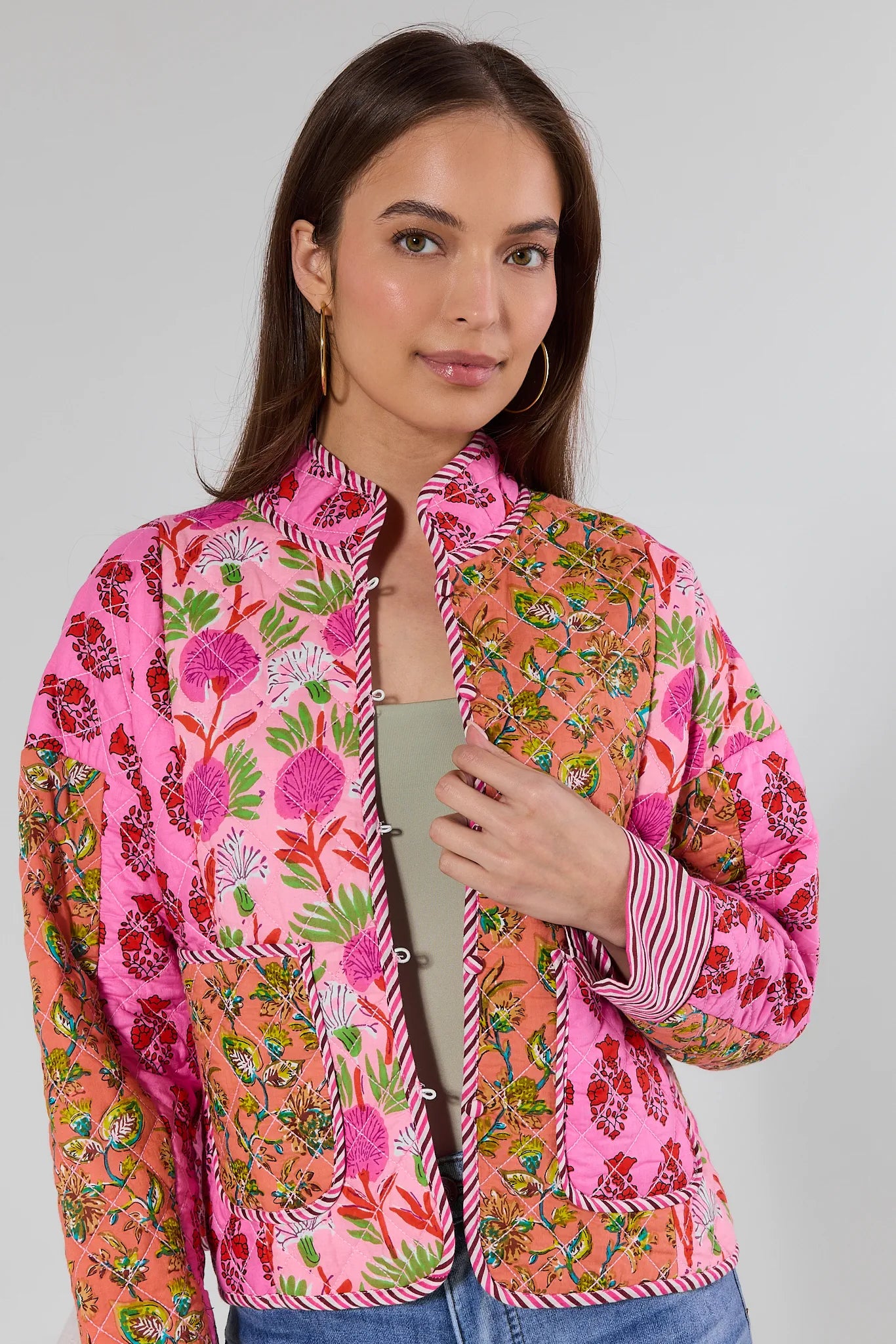 Woman wearing a colorful floral jacket on a plain background