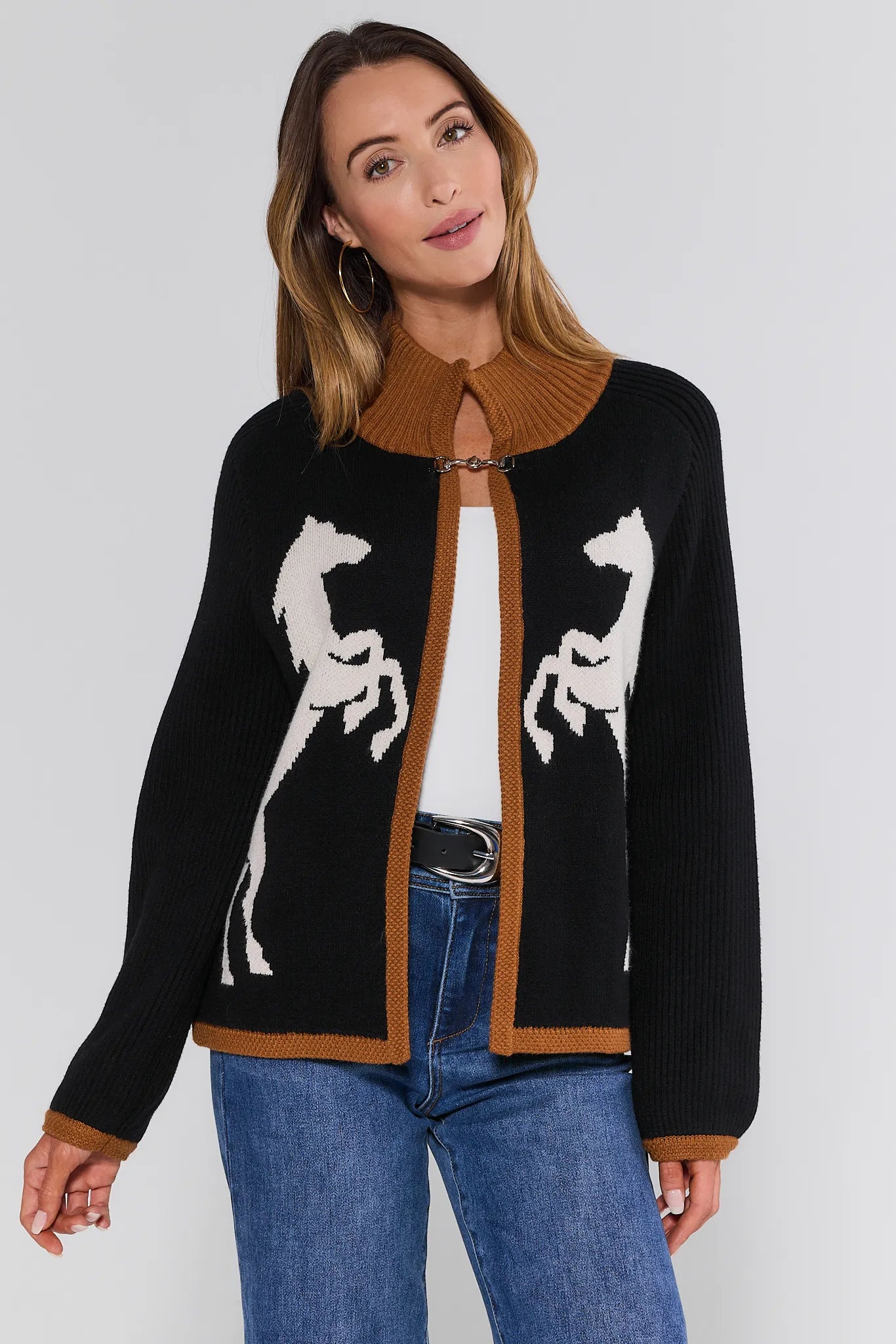 Woman wearing a black Cheyenne Cardigan with horse designs on a plain background