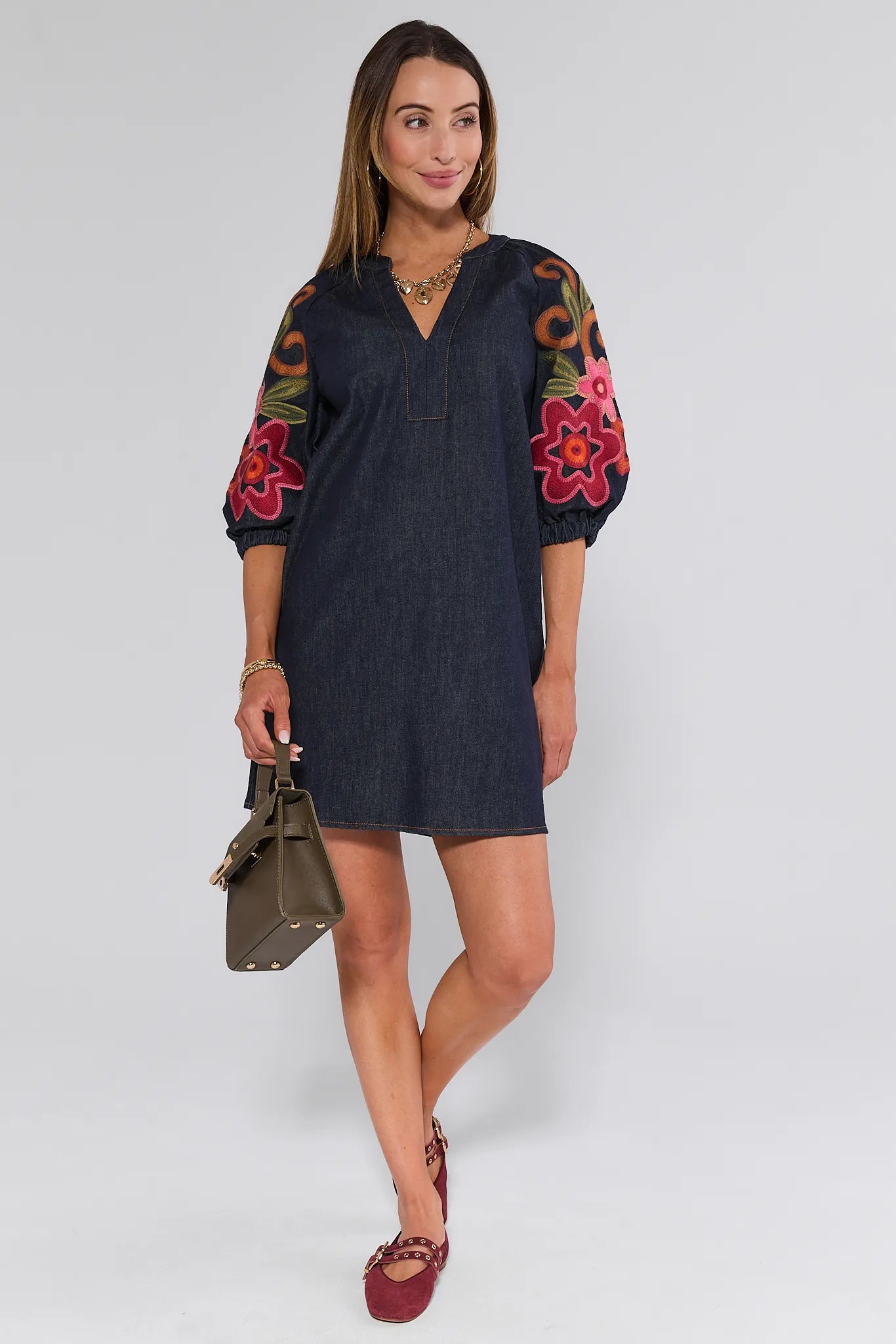 Woman wearing a dark blue Winnifred Dress with colorful floral patterns on a white background