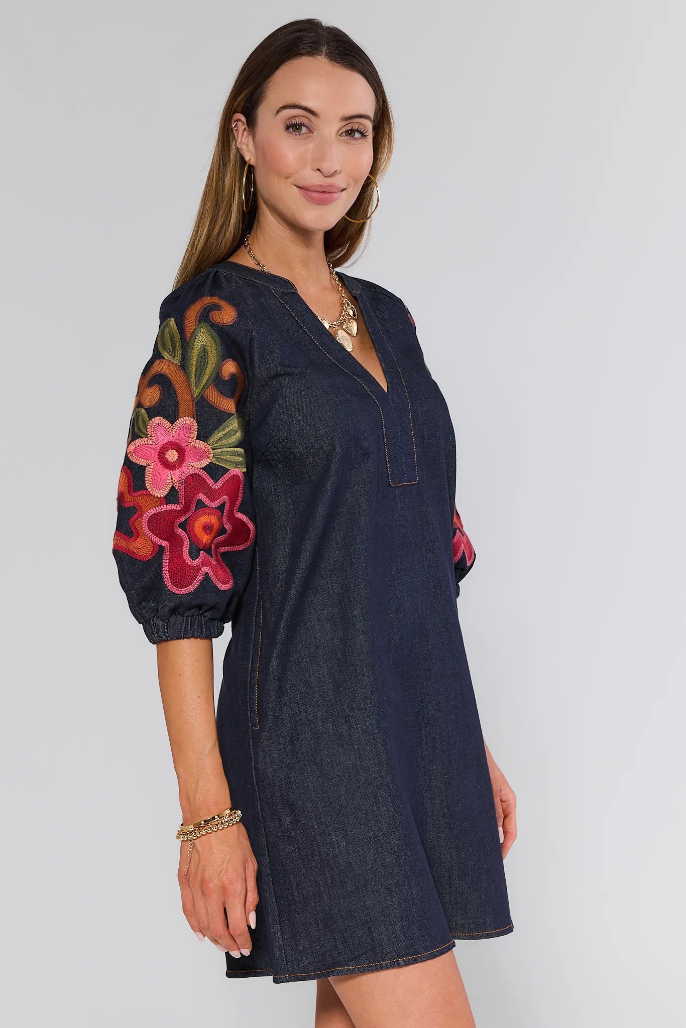Woman wearing a dark blue Winnifred Dress with floral embroidery on sleeves against a white background