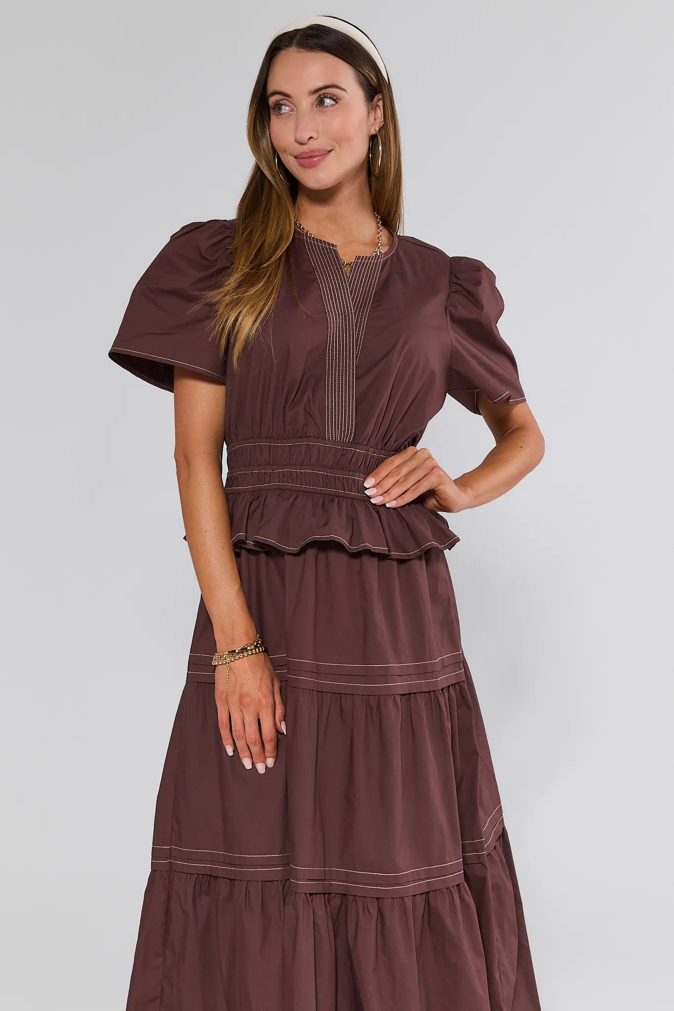 Woman wearing a brown Cherish Dress with puffed sleeves against a white background