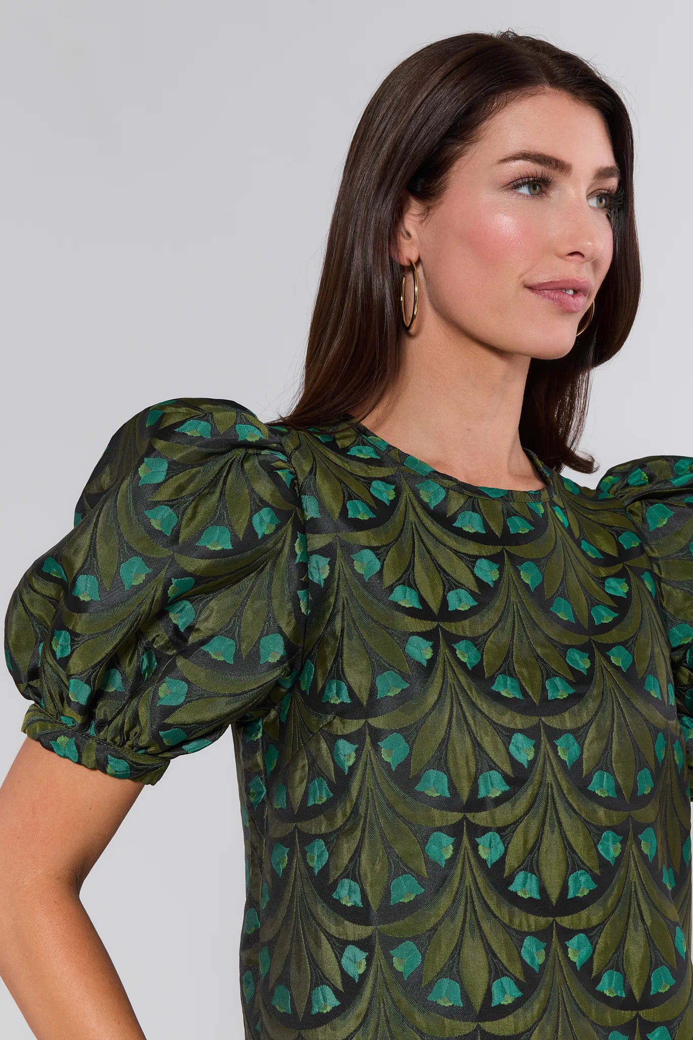 Woman wearing a green and teal patterned Raquel Top with puffed sleeves against a plain background