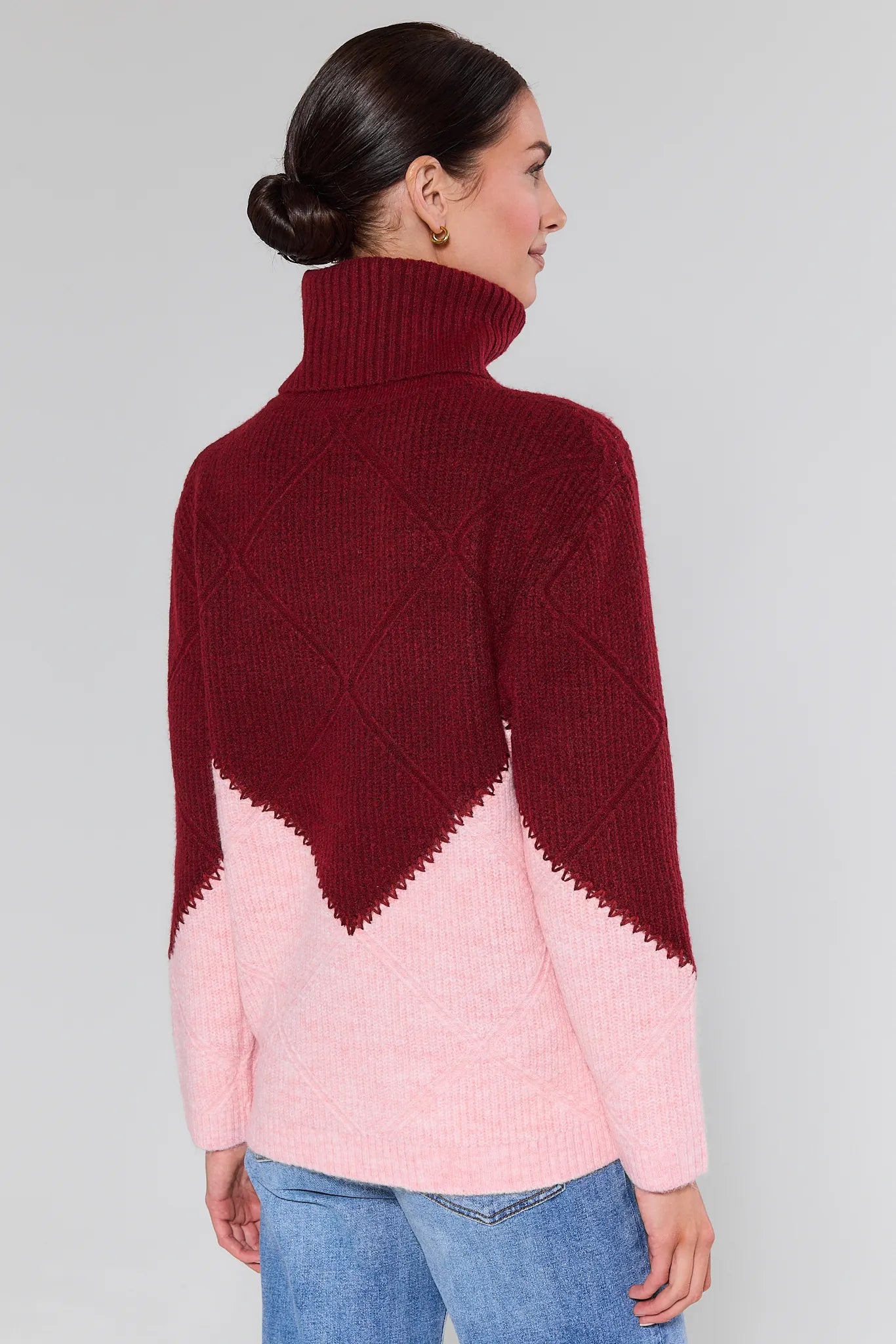 Woman wearing a Bianca Colorblock Turtleneck Sweater maroon and pink with a white background
