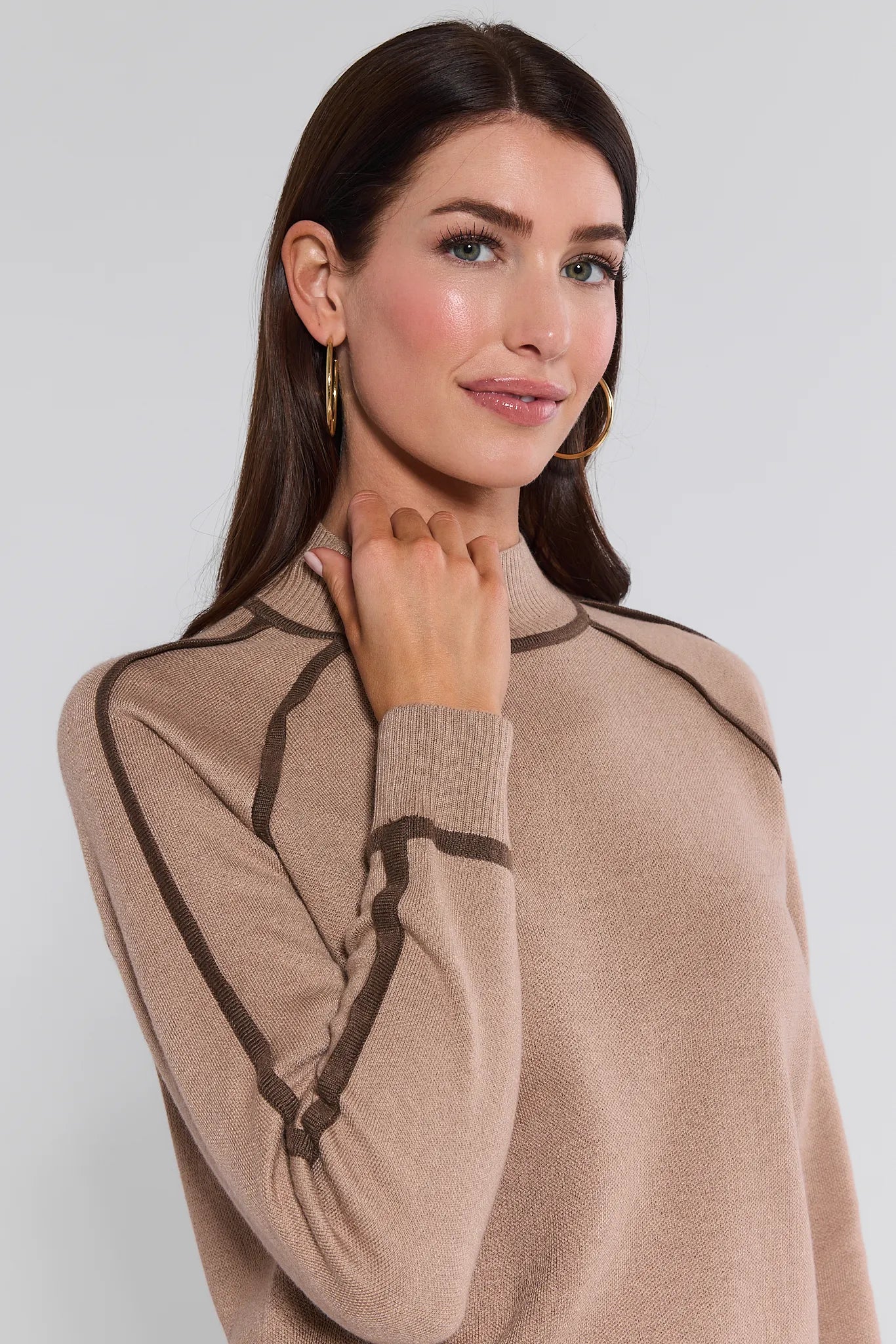 Woman wearing a beige Agnes Sweater
 with brown accents on a plain background