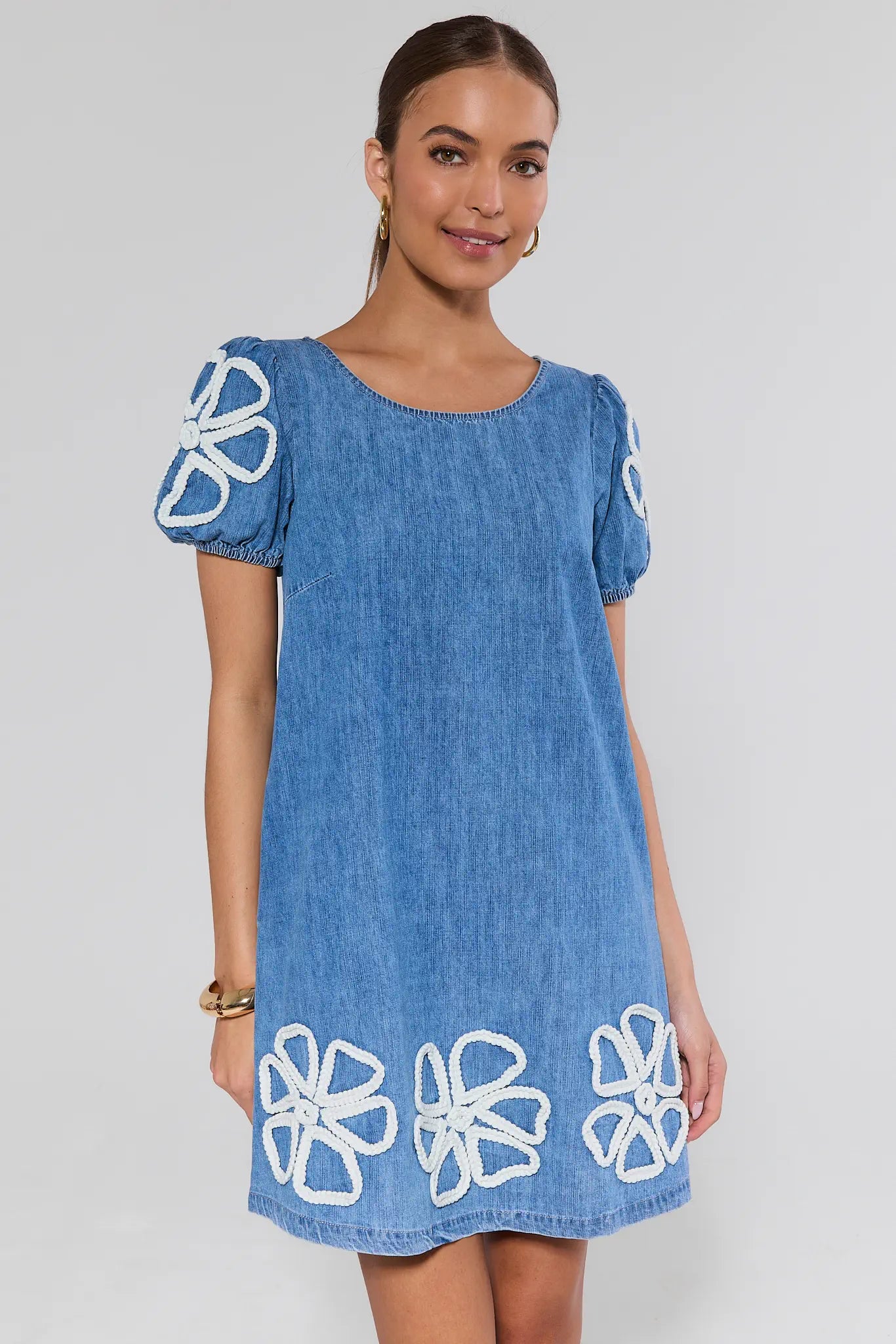 Woman wearing a blue dress with white floral patterns on a gray background