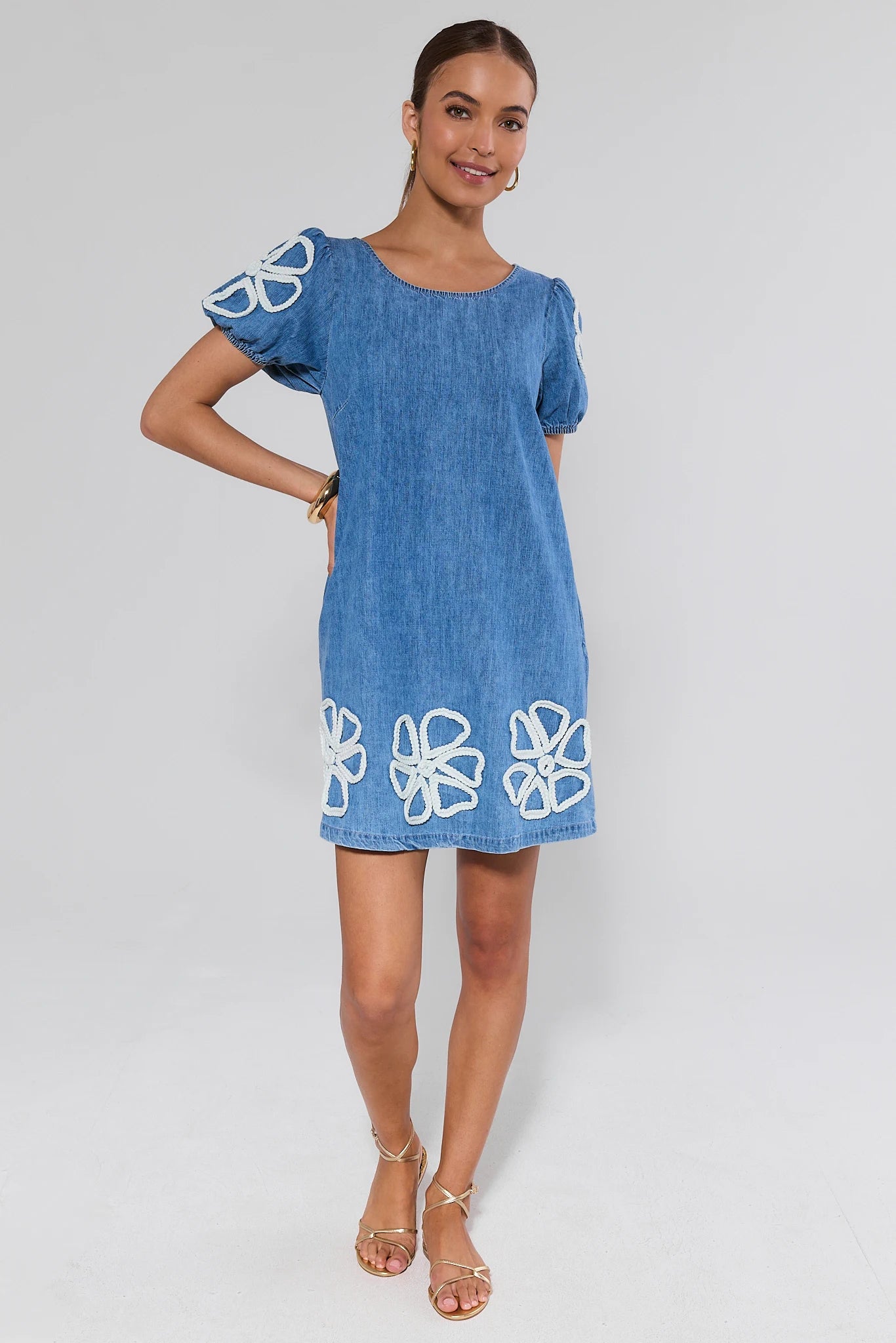 Woman wearing a blue dress with white floral patterns on a plain background