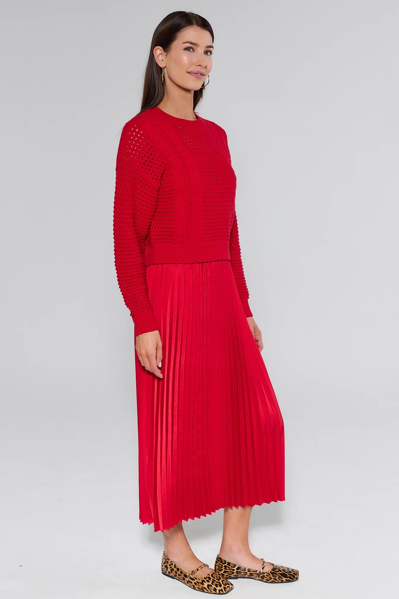 Woman wearing a red knitted and pleated gabbie dress against a white background