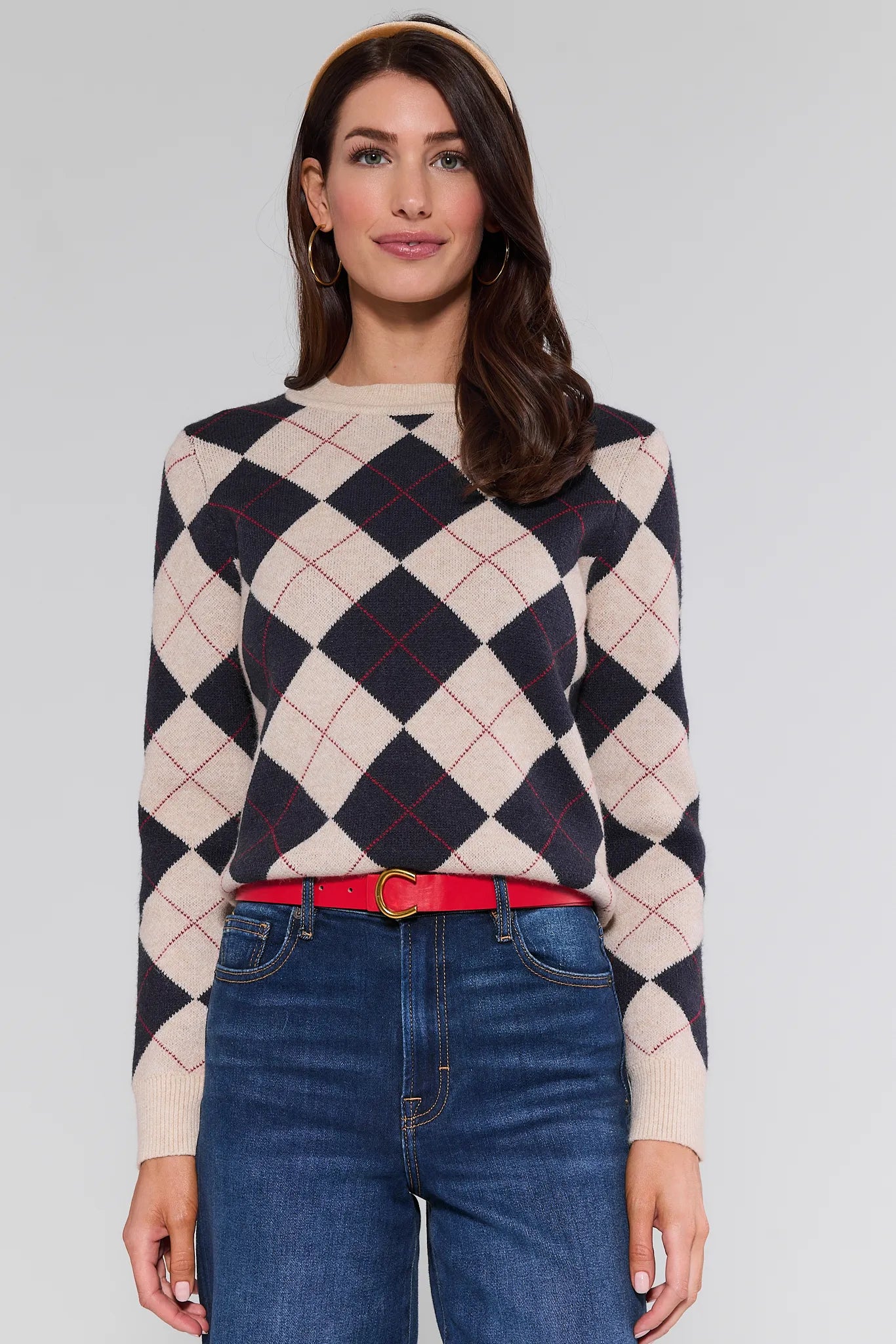 Woman wearing a patterned Winifred Sweater and jeans on a plain background
