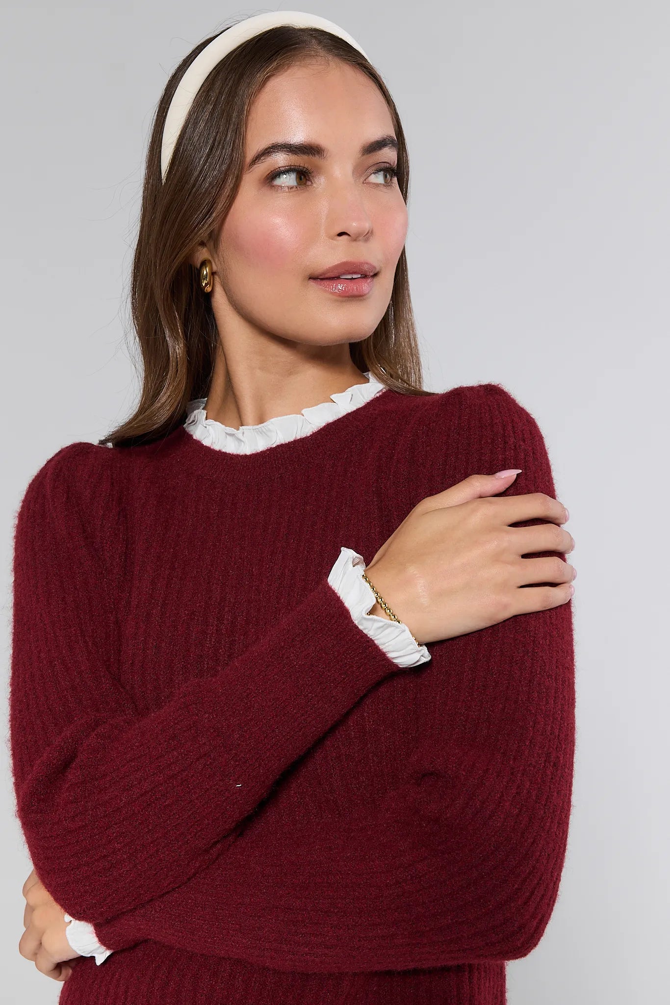 Woman wearing a burgundy Annabelle Sweater with a white collar against a gray background