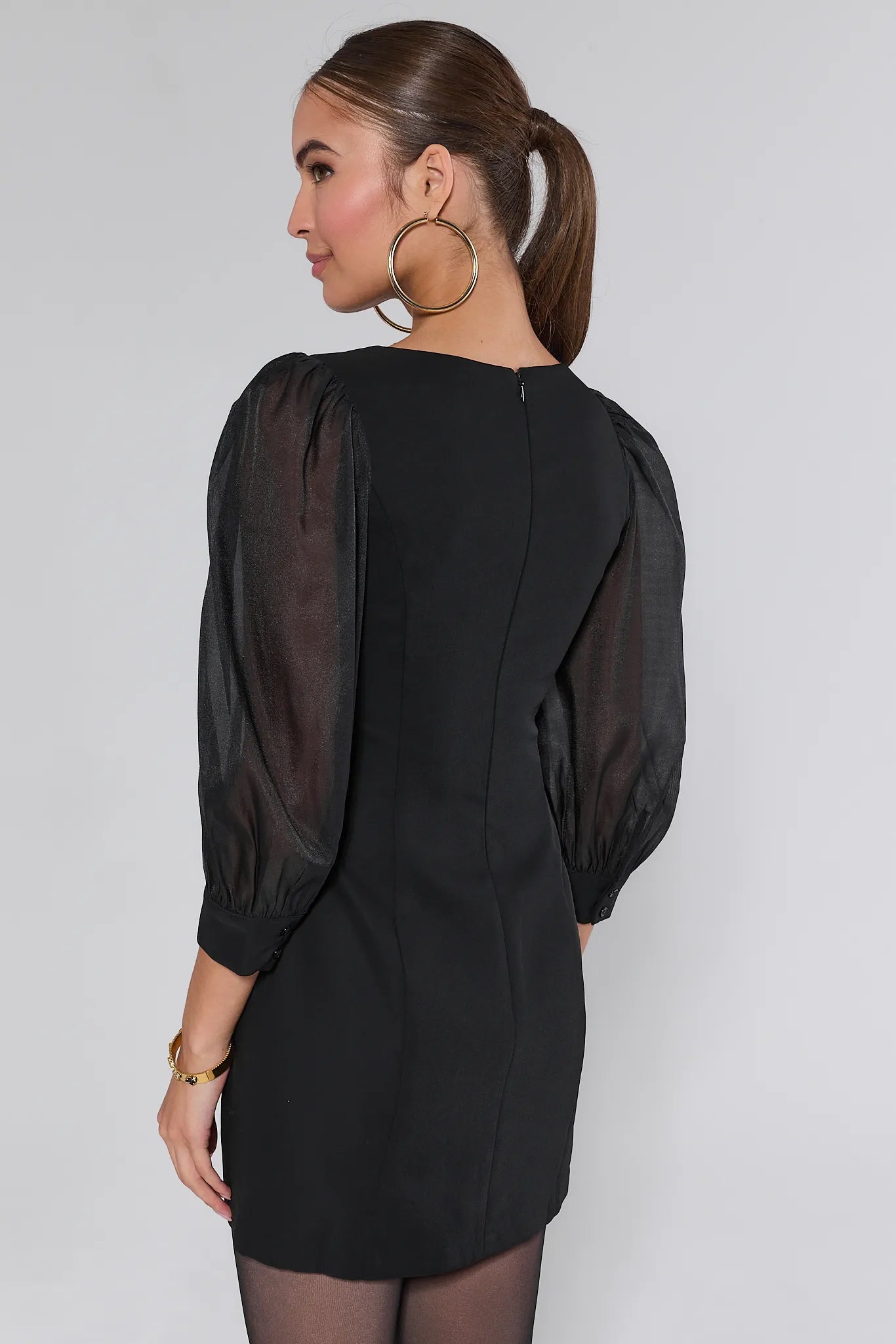 Woman wearing a black Veronica Dress with sheer sleeves against a plain background